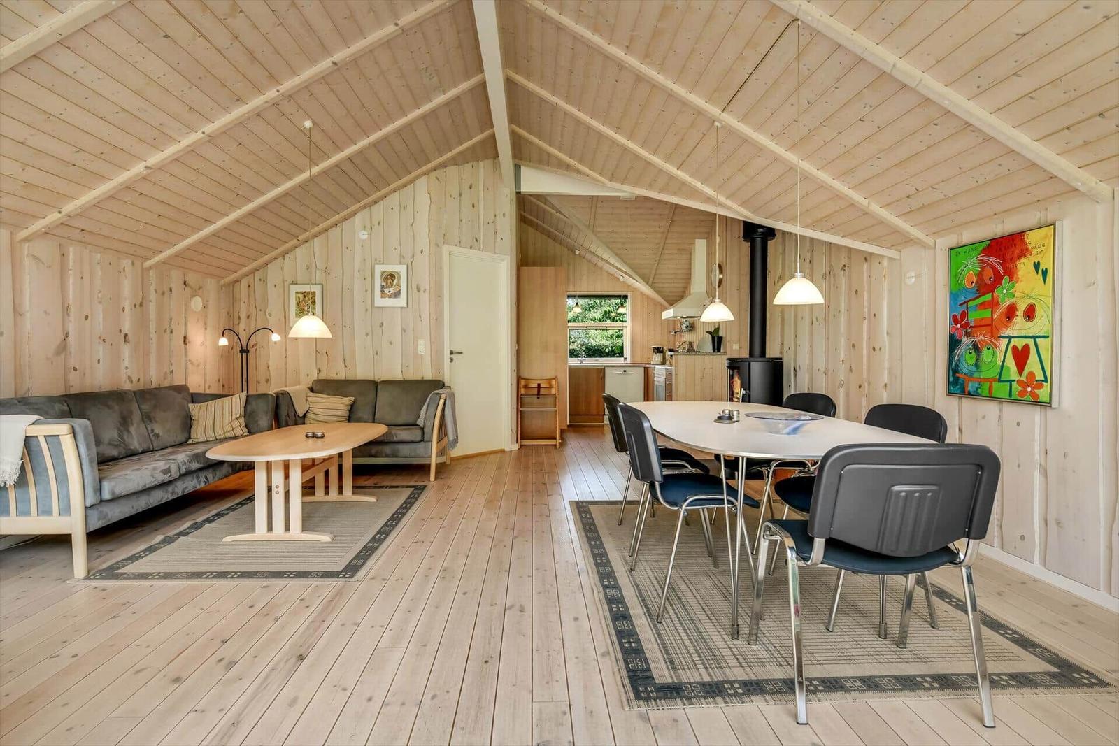 Wohn- und Essbereich mit Holzdecke, Sofa, Tisch und Stühle.