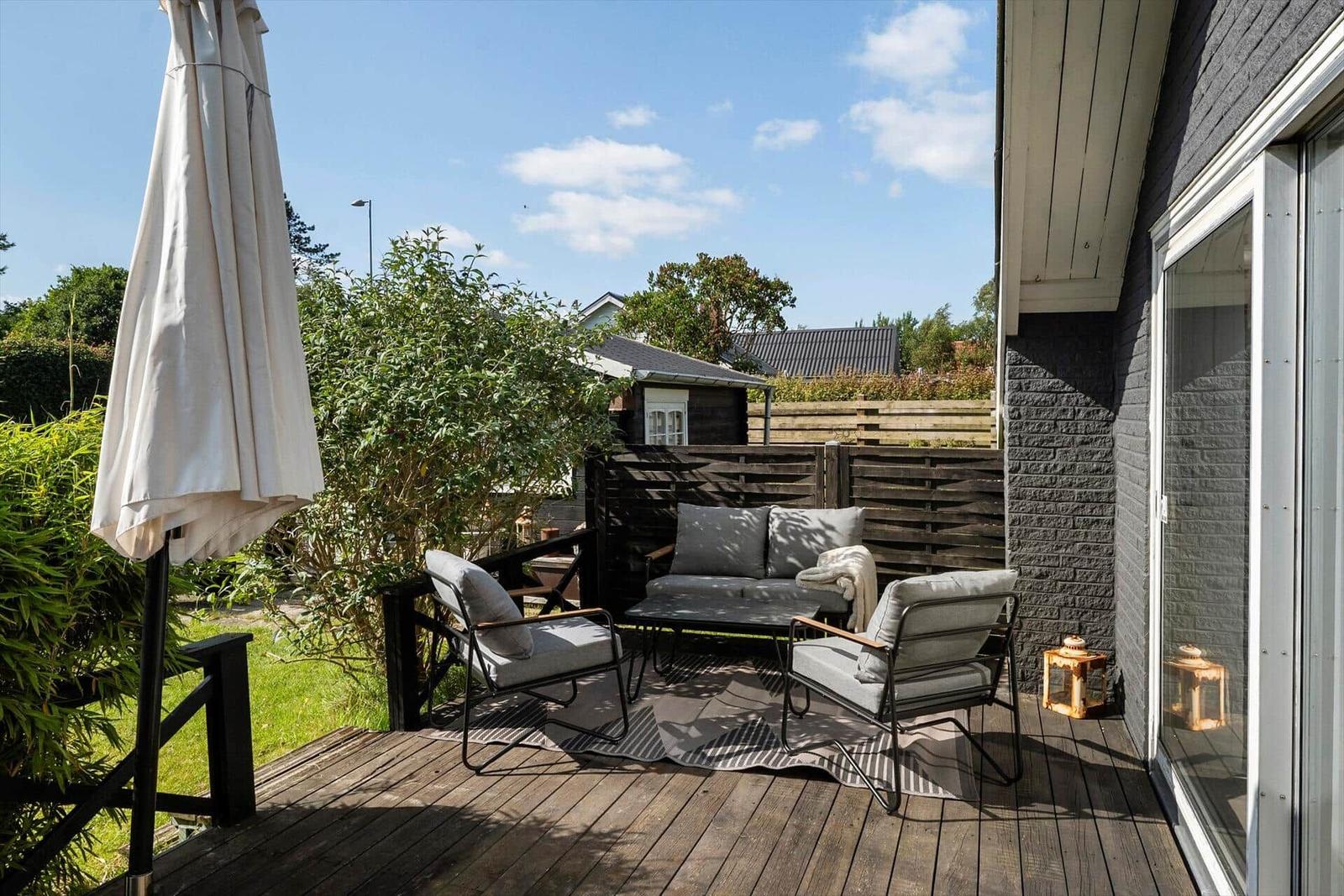 Terrasse mit Sitzgruppe, Sonnenschirm und Gartenansicht.