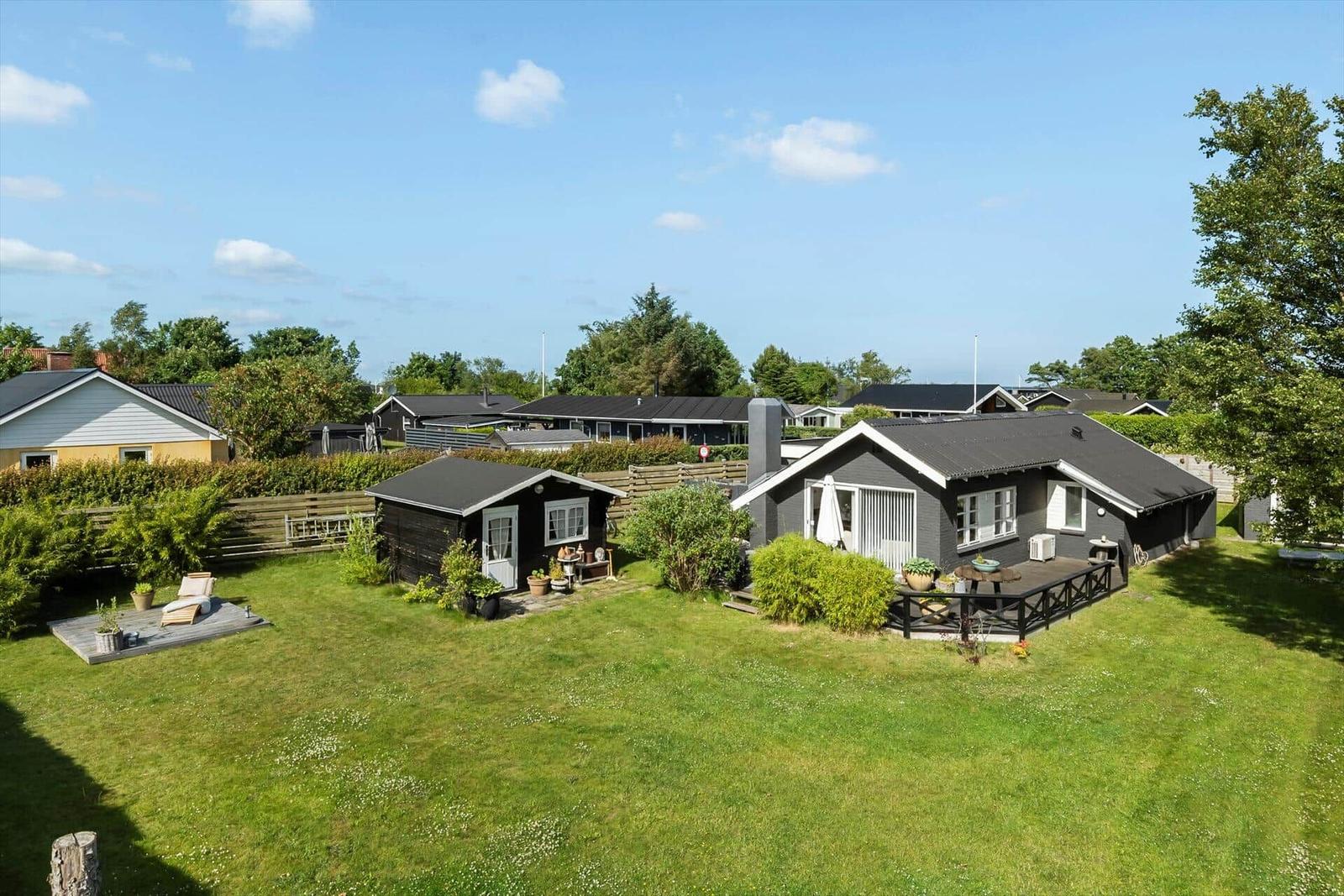 Schwarze Ferienhaus mit Terrasse und Garten. Hinterhof mit Holzveranda und Liegestühlen.