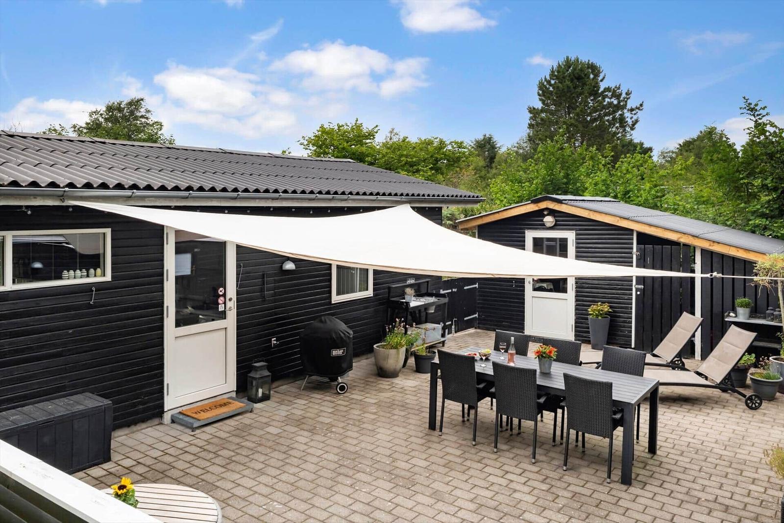 Terrasse mit Tisch, Stühlen und Sonnensegel. Grill und Liegestühle sind vorhanden.