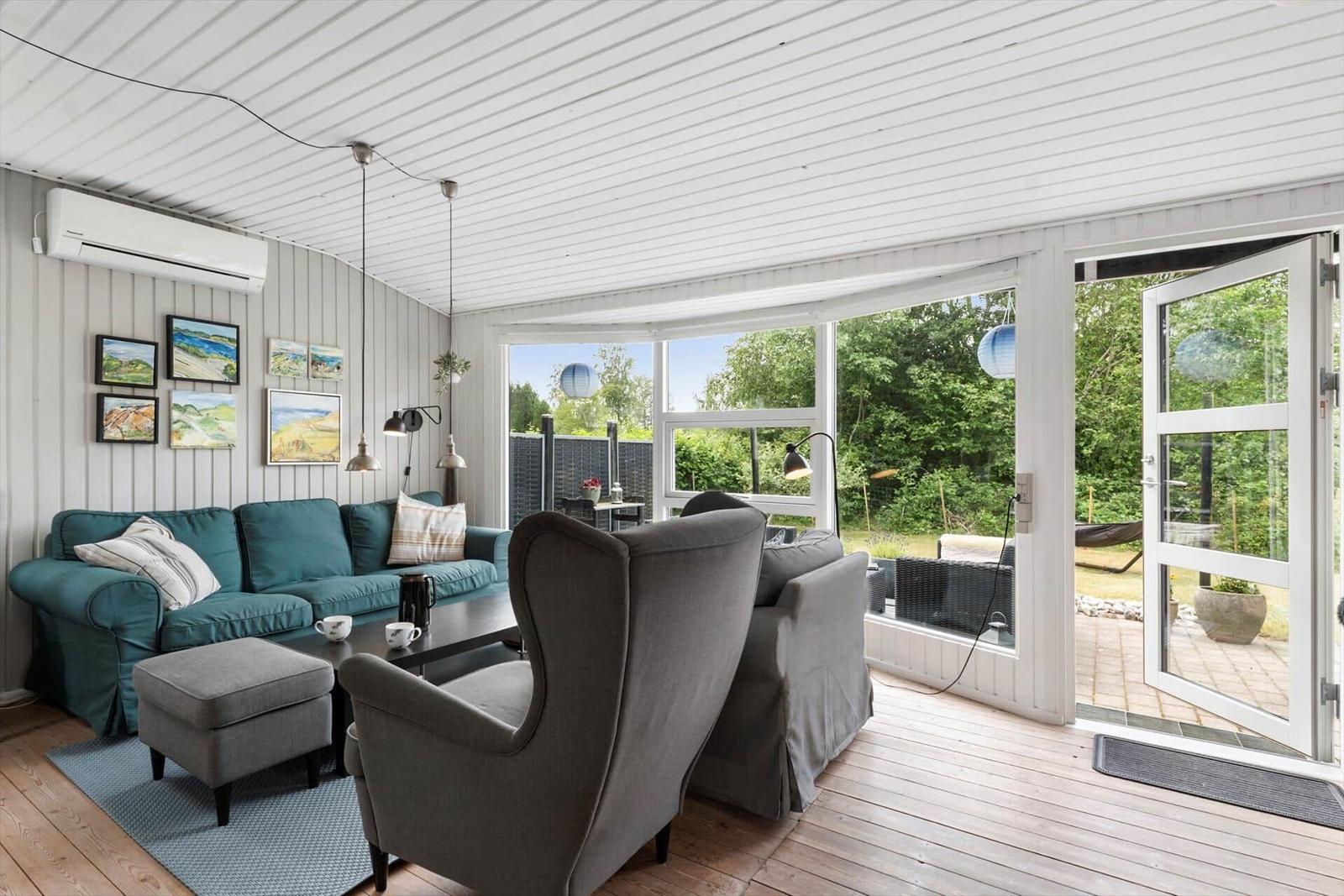Wohnzimmer mit Sofa, Sessel und Blick auf die Terrasse.