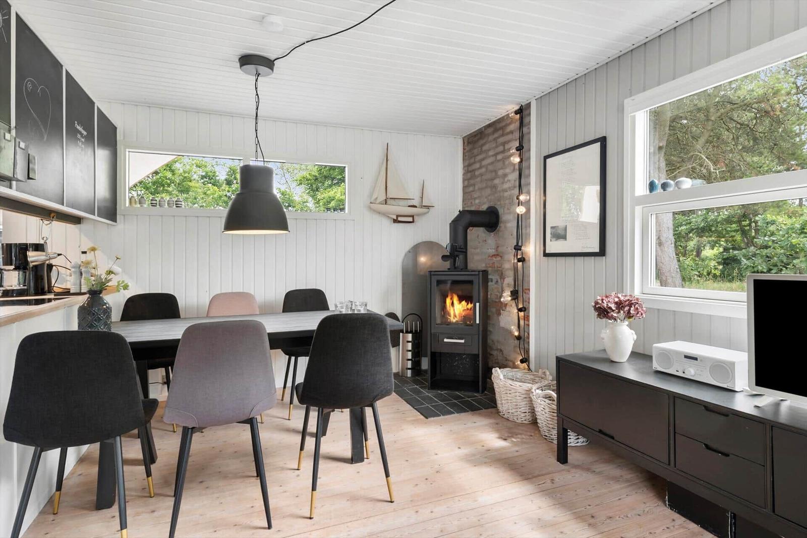 Essbereich mit Tisch, Stühlen und Kaminofen an der Wand.