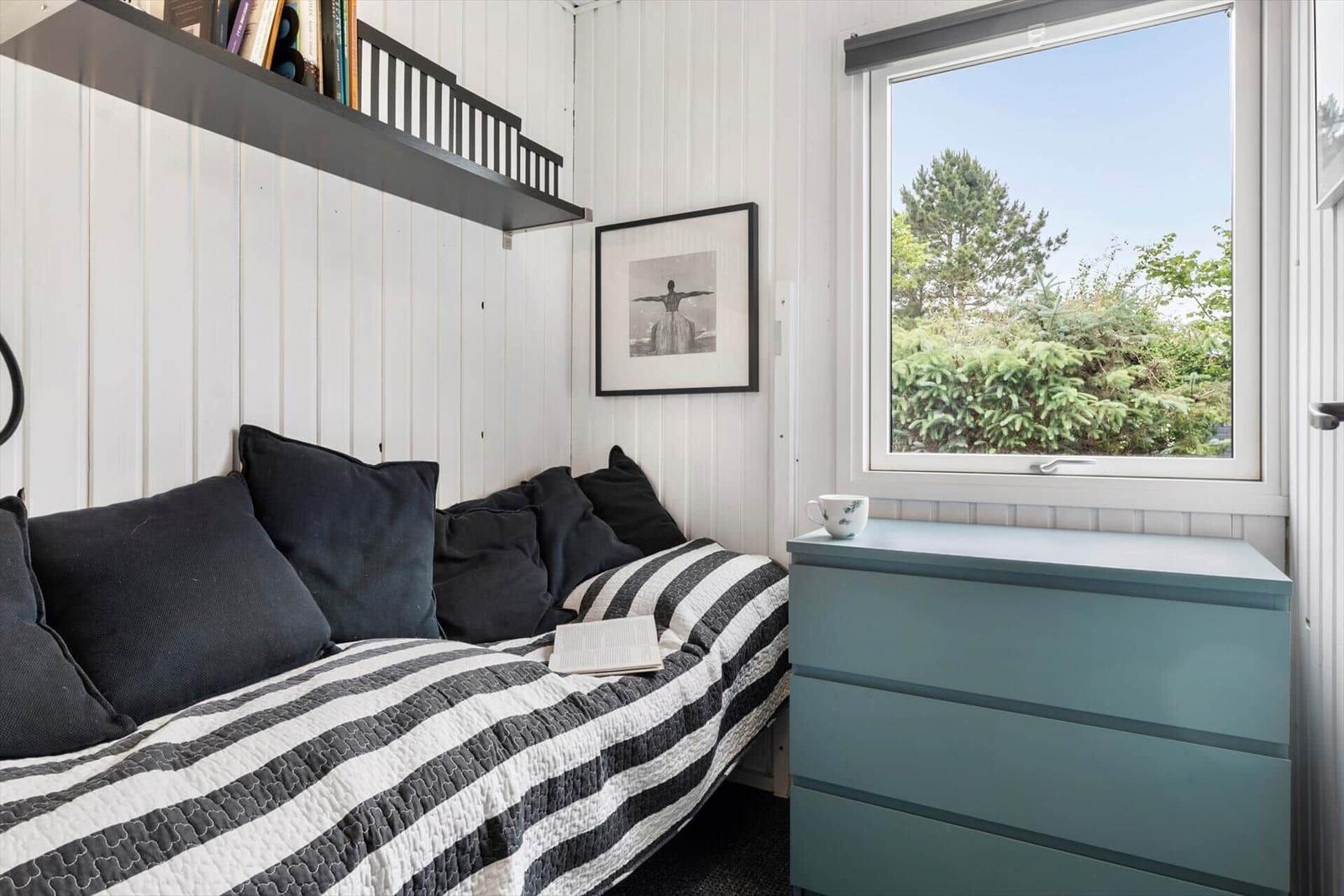 Schlafzimmer mit Bett, Schrank und Fensterblick auf Grünflächen.