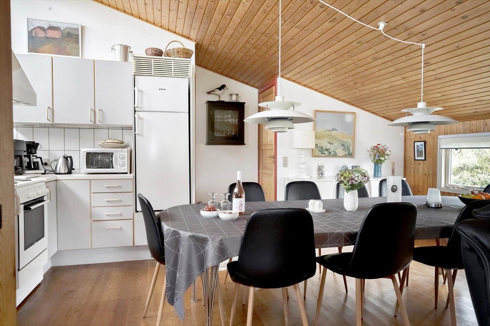 Küche und Essbereich mit Holzdecke und moderner Beleuchtung.