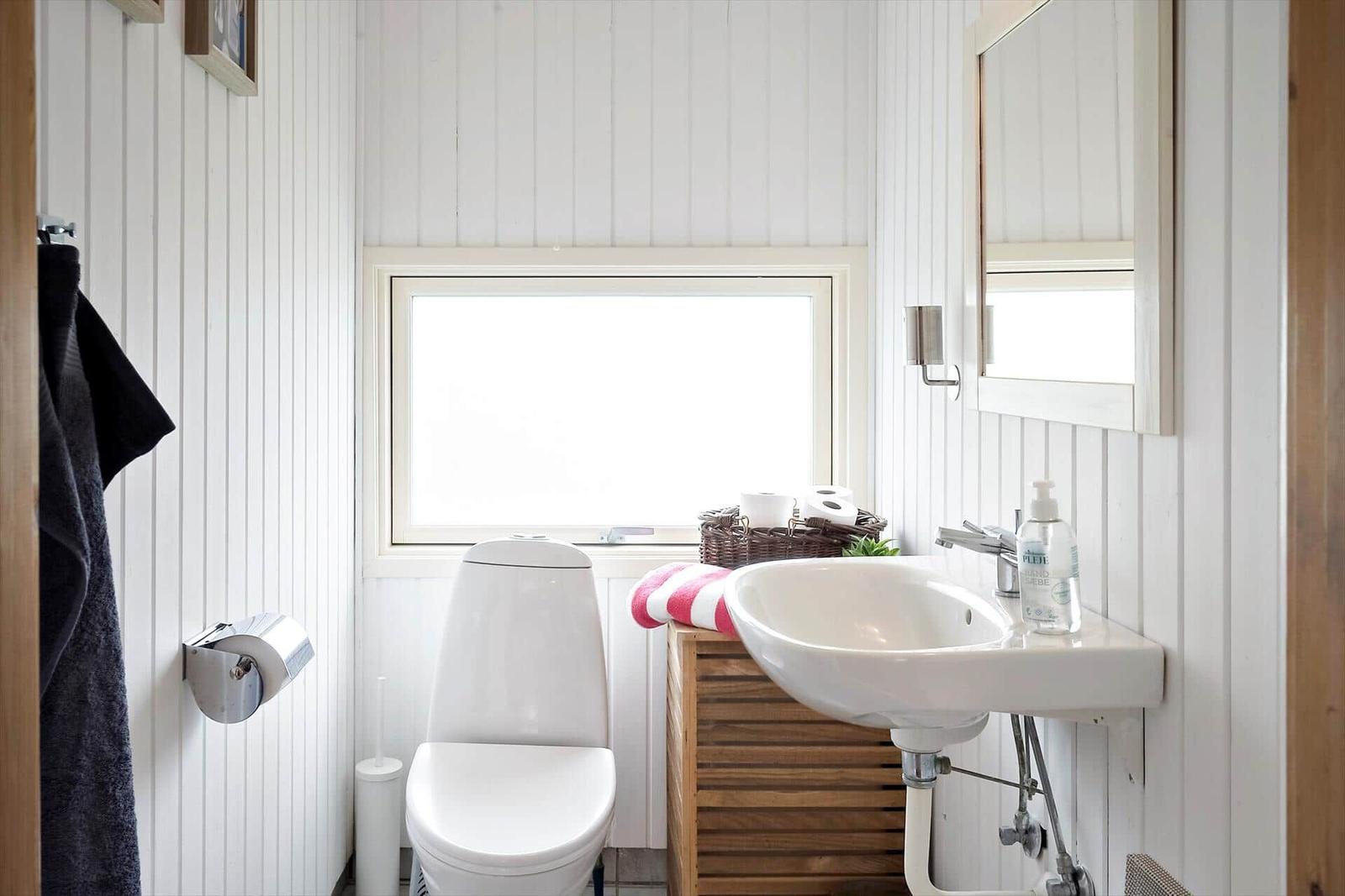 Badezimmer mit Toilette, Waschbecken und Fenster.