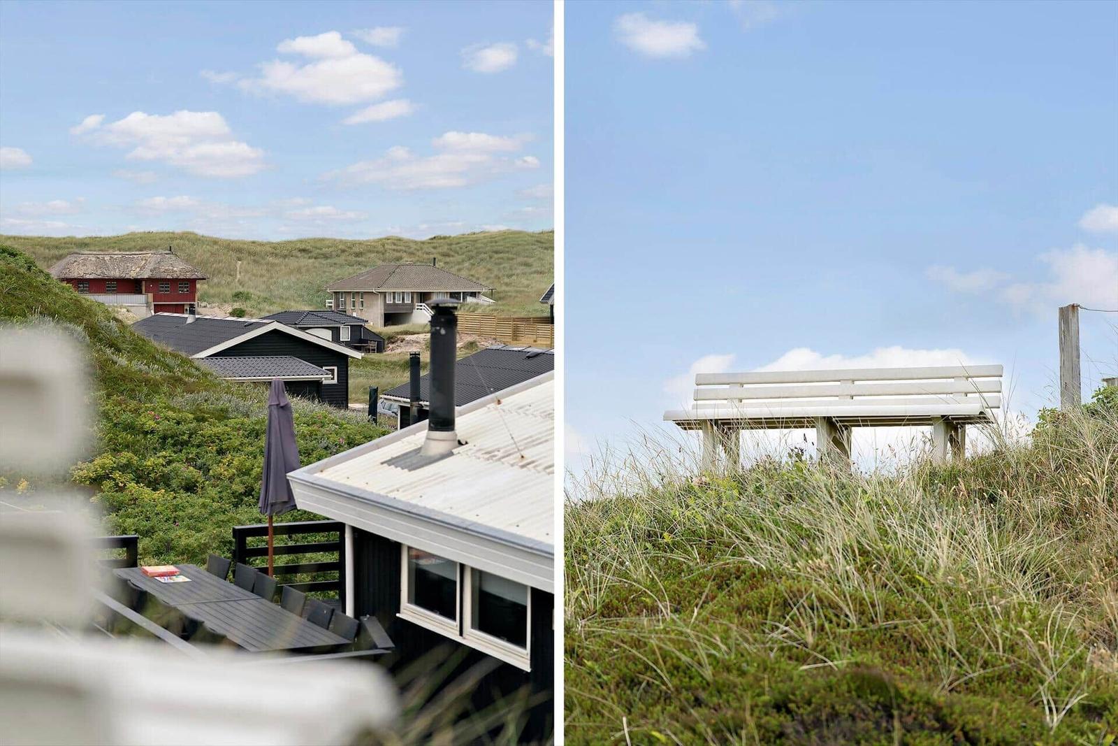 Dachterrasse mit Blick auf grüne Dünen und Ferienhäuser. Weiße Bank auf einer Düne.