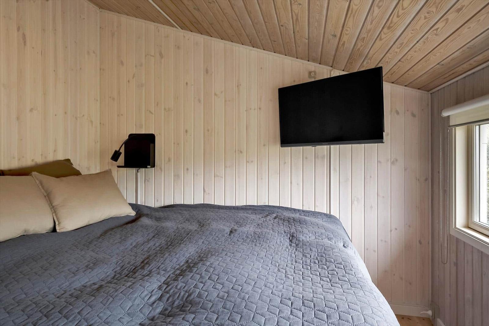 Schlafzimmer mit Bett, Wand-TV und Fenster