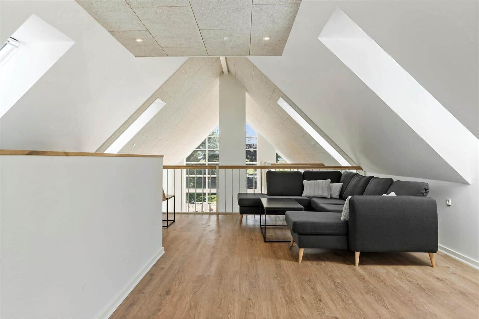 Dachgeschosswohnung mit Sofa, Holzboden und Dachschrägen.