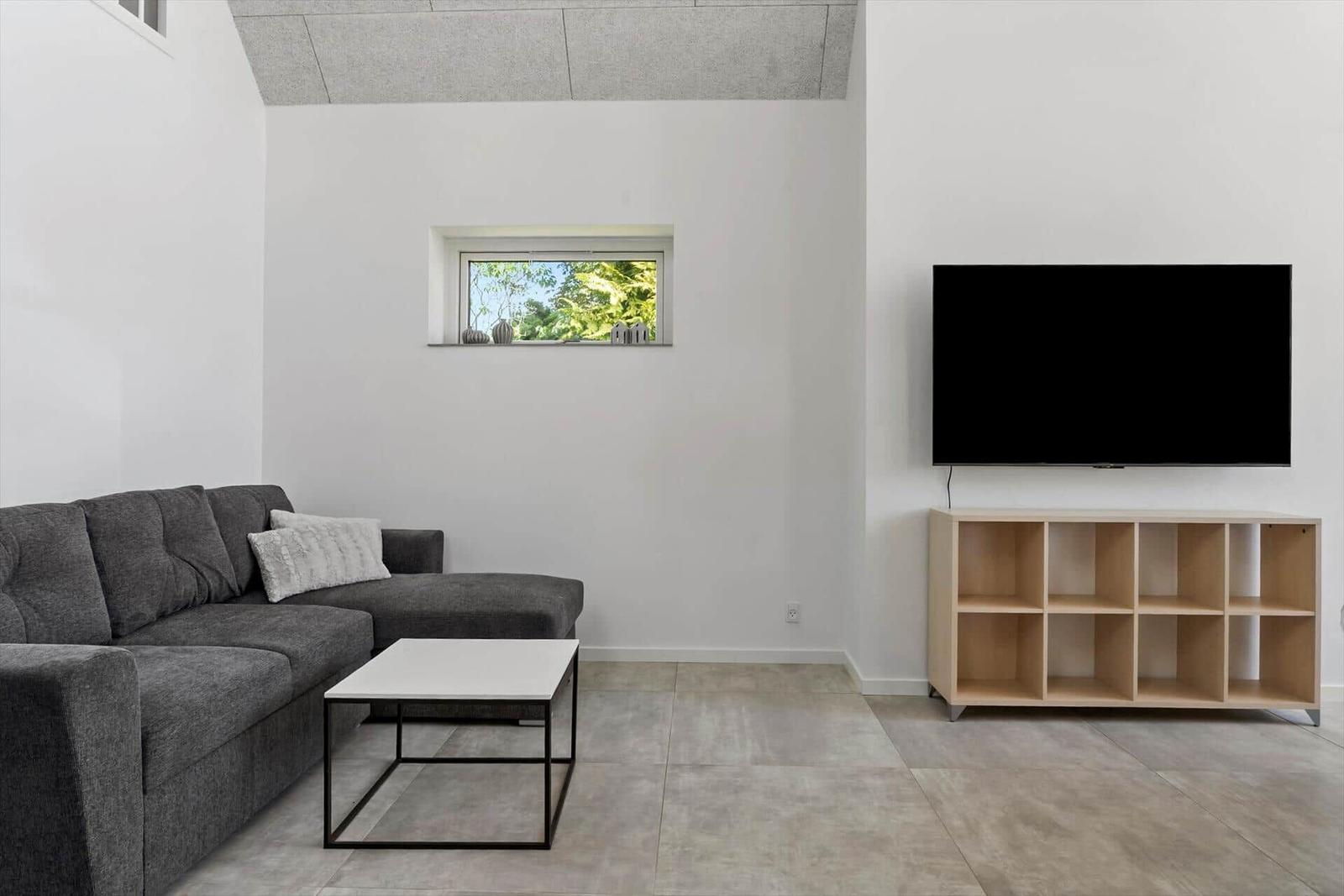 Wohnzimmer mit Sofa, Couchtisch und Fernseher an der Wand.