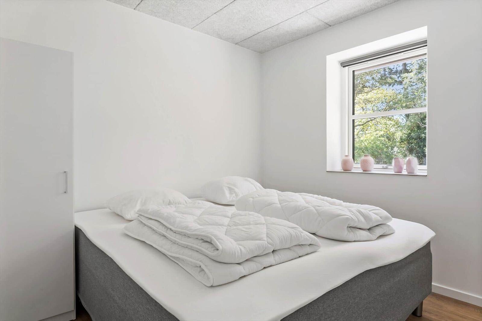 Schlafzimmer mit Bett, Fenster und Schrank.