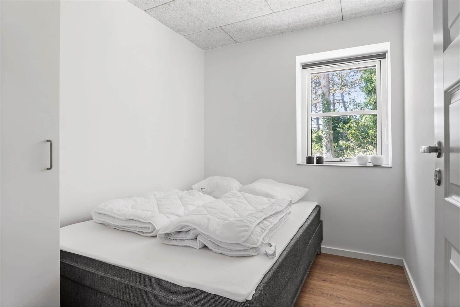 Schlafzimmer mit Bett, Fenster und Holzboden.