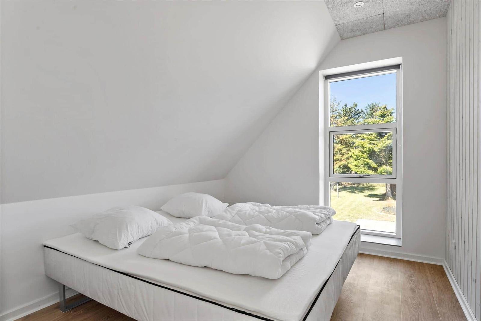 Schlafzimmer mit Doppelbett und Fensterblick auf Grünfläche