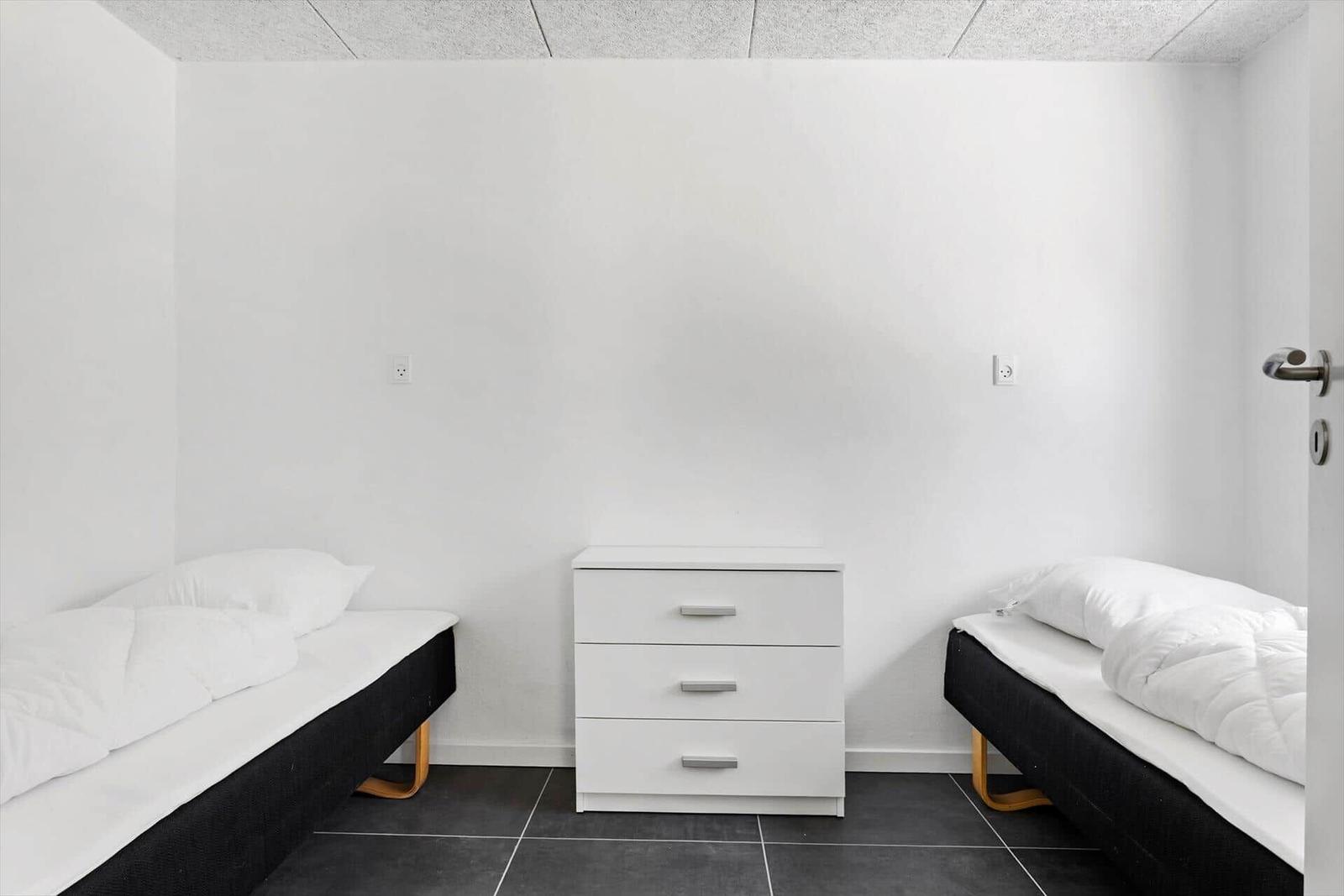 Zimmer mit zwei Einzelbetten und einem weißen Schrank.