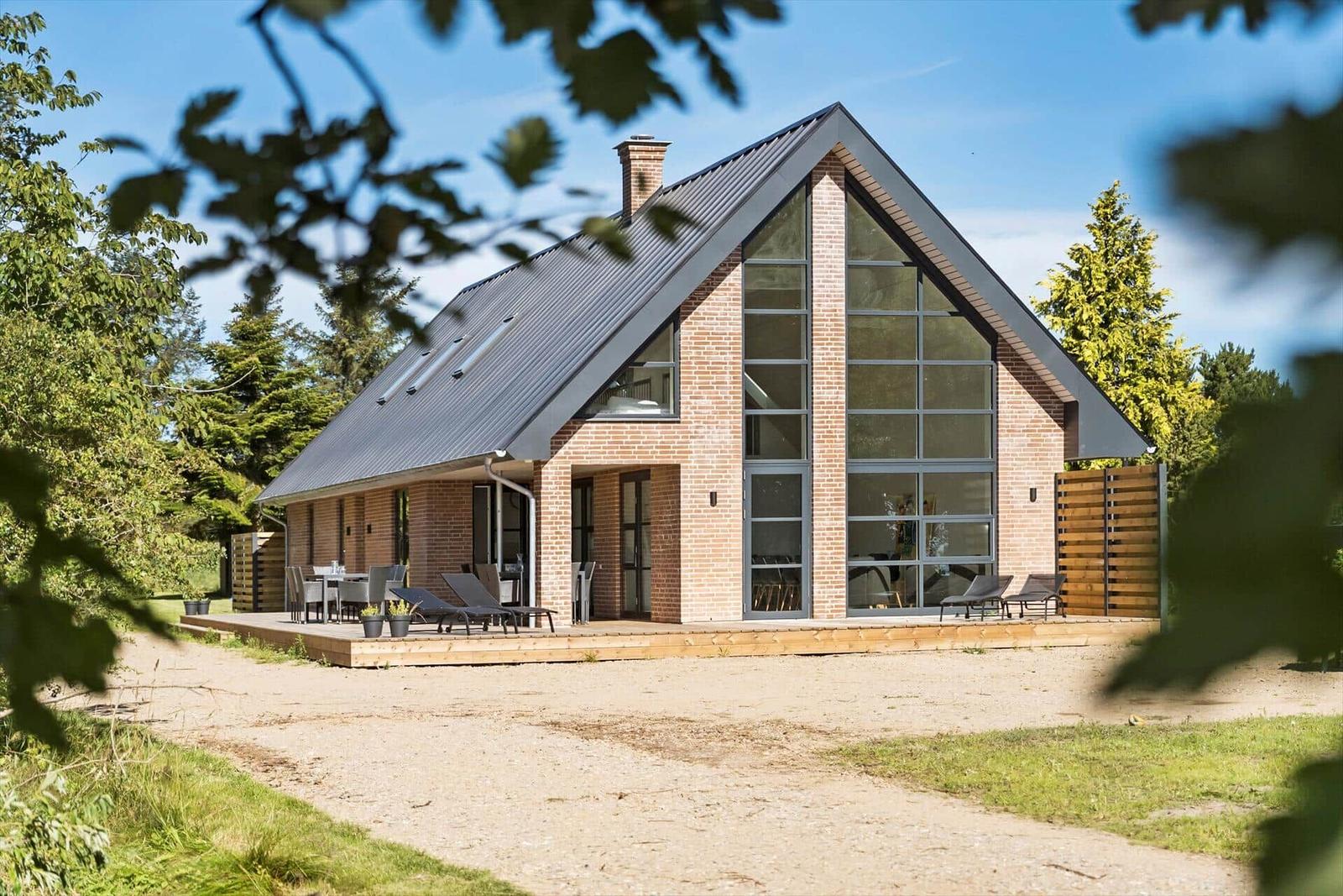 Moderne Villa mit Holzterrasse und großem Glasfassade im Grünen.