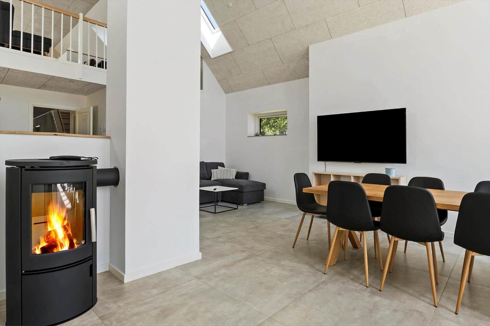 Wohn- und Essbereich mit Kamin, TV und Balkonzugang.