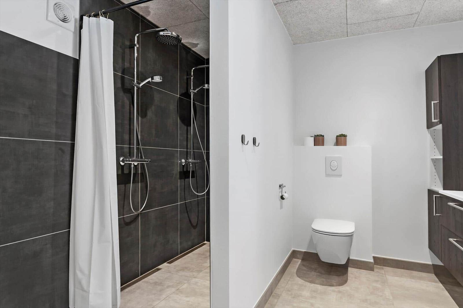 Dusche mit Duschvorhang, Toilette und Waschbecken mit Schrank.