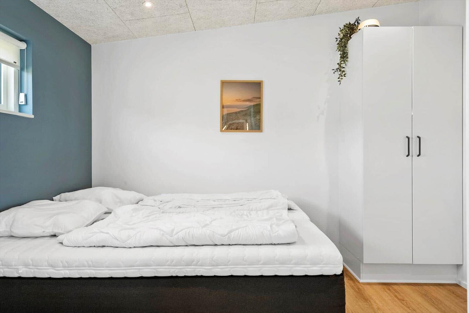 Schlafzimmer mit Bett, Kleiderschrank und Wandbild.