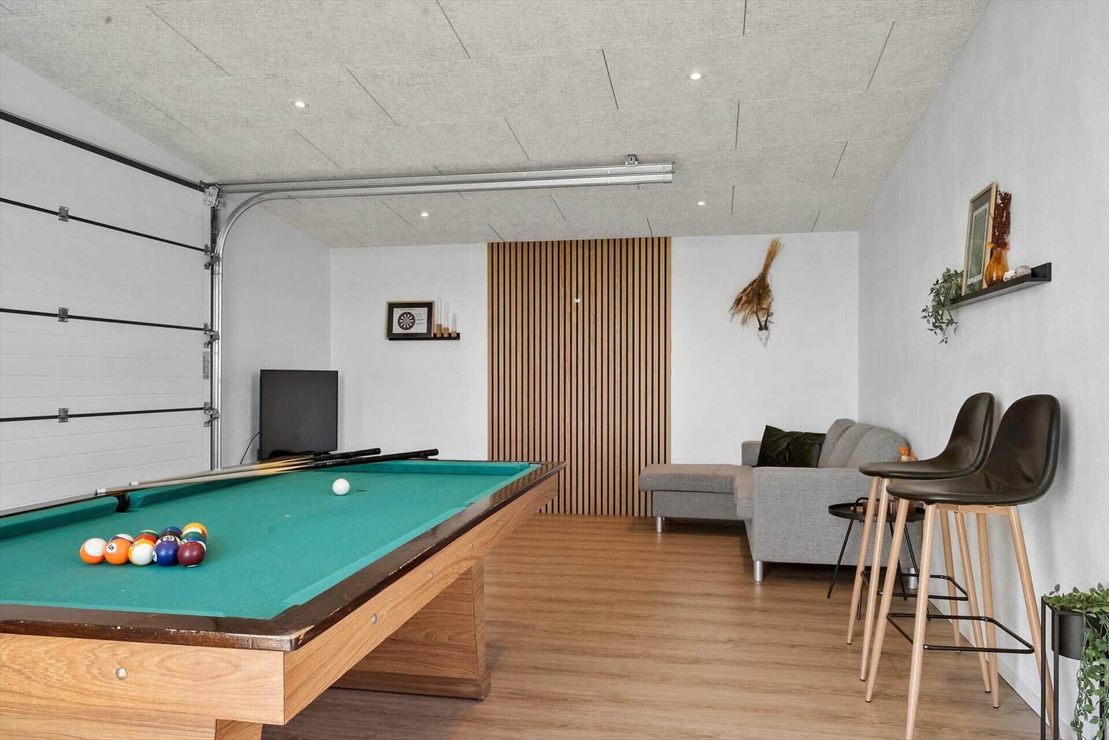 Billardtisch mit Bällen, Sofa und Barhocker im Raum.