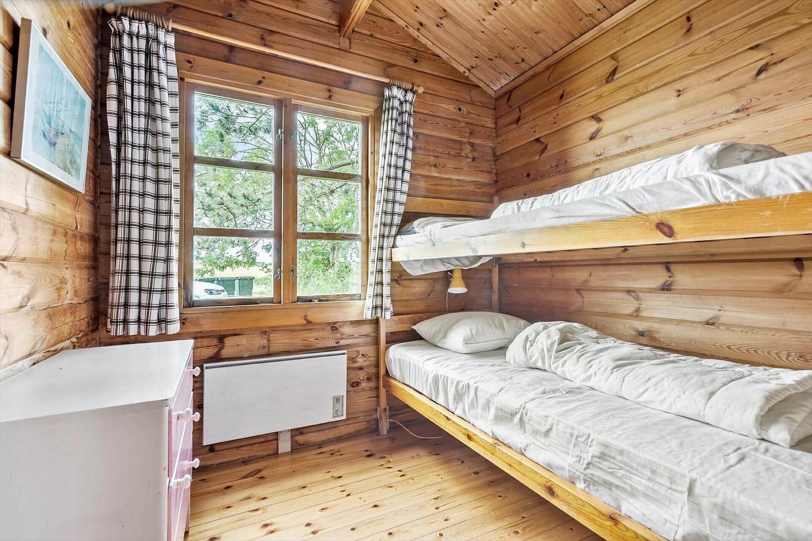Room with wooden walls, window, heater, and bunk bed.
