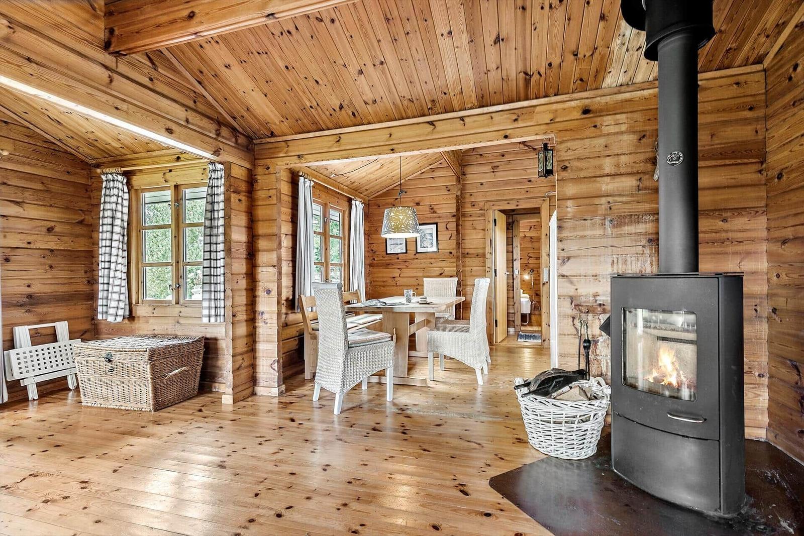 Log cabin with fireplace, dining table, and windows.