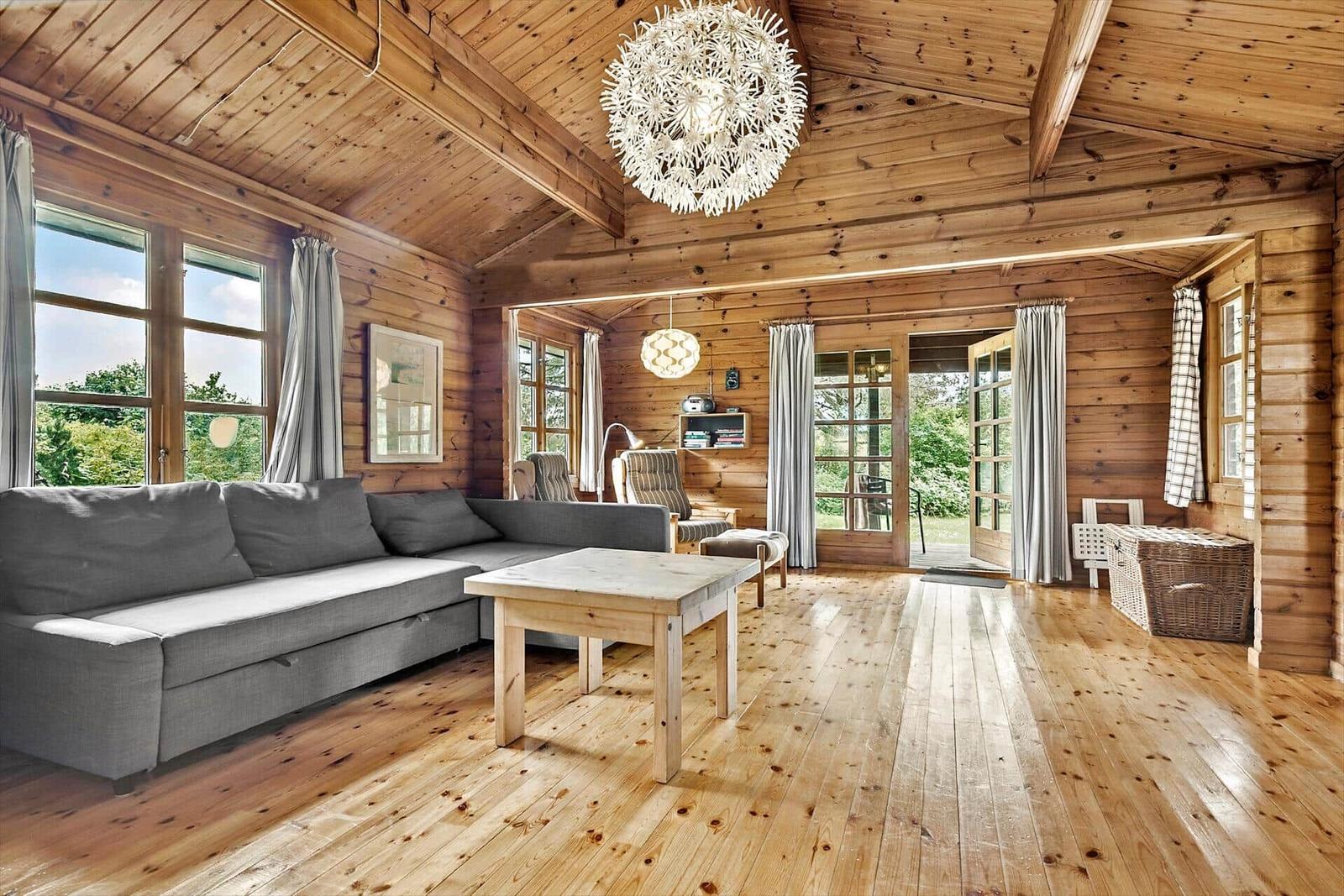Living room with wooden ceiling, sofa, table, and windows.