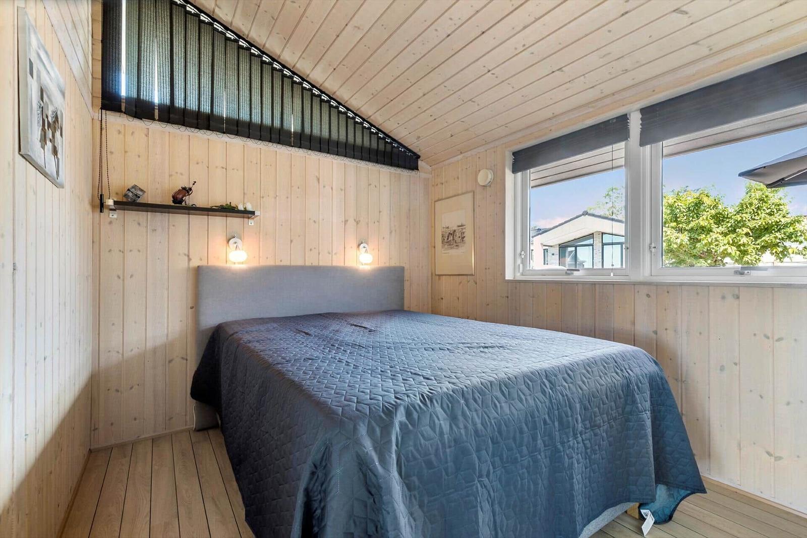 Schlafzimmer mit Holzwänden, großem Bett und Fenster mit Blick.