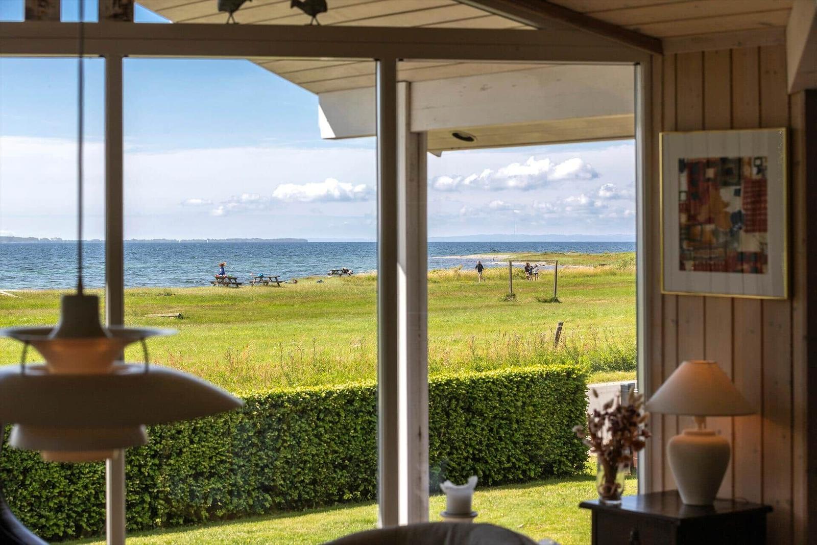Durch die Glasfront blickt man auf einen grünen Rasen und das Meer.