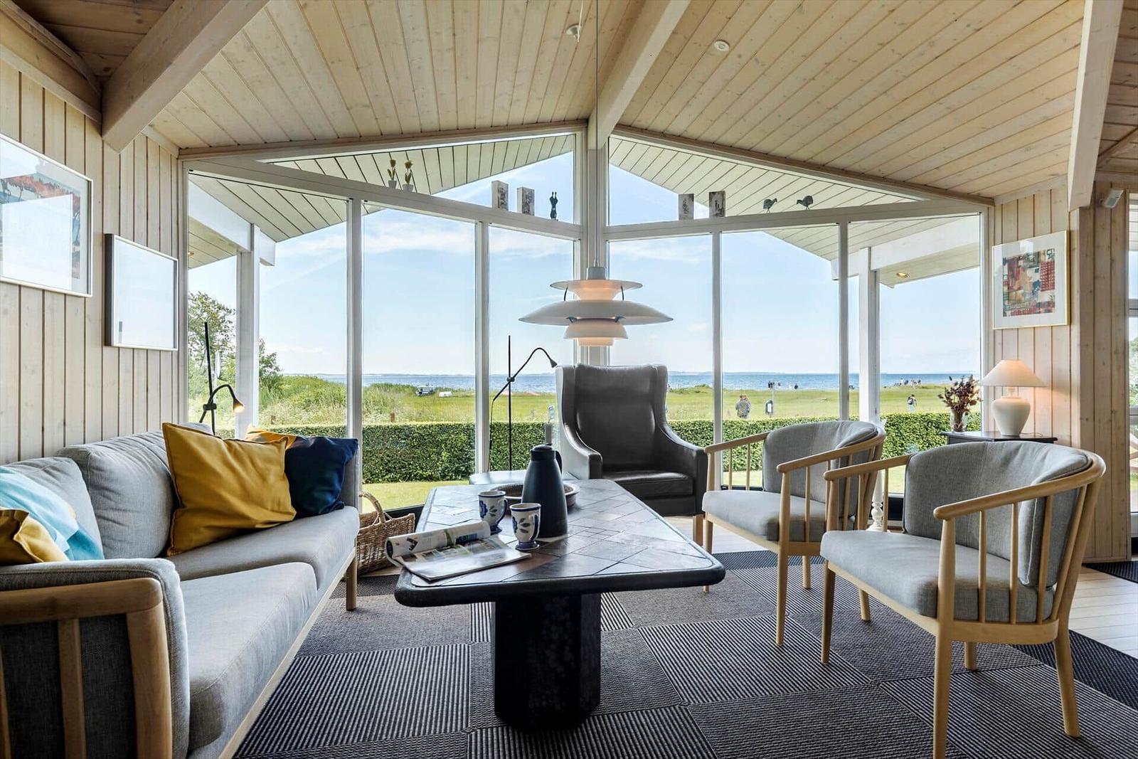 Wohnzimmer mit Blick auf Strand und Meer durch große Fenster.