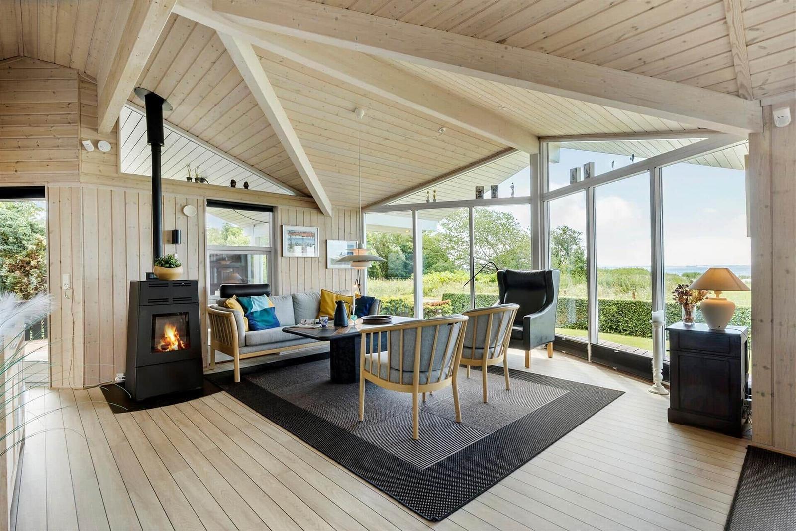 Wohnzimmer mit Kamin, Sofa und Sicht auf Grünland.