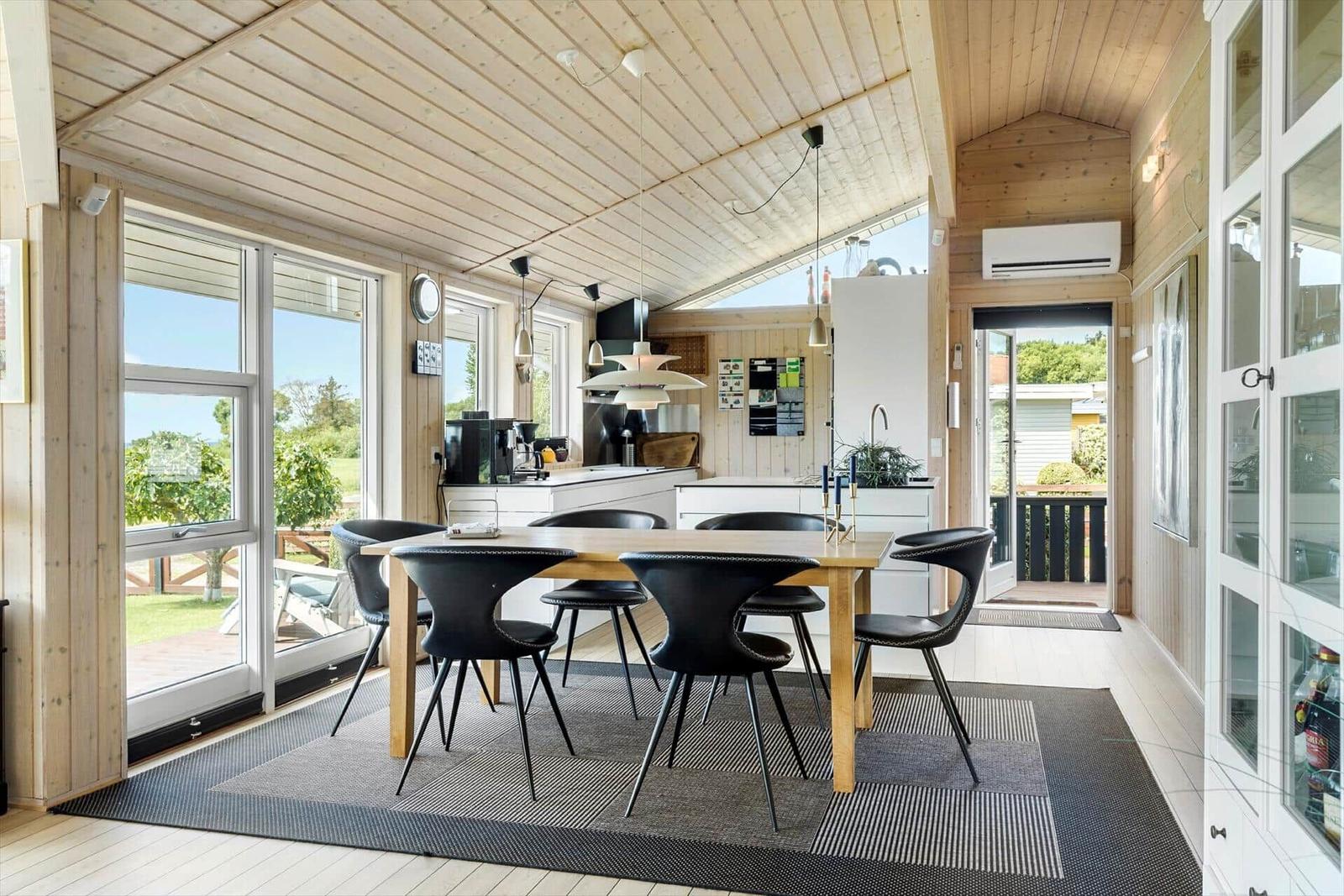 Essbereich mit Tisch, Stühlen und Blick auf Garten. Küche mit Arbeitsplatte und Fenster.