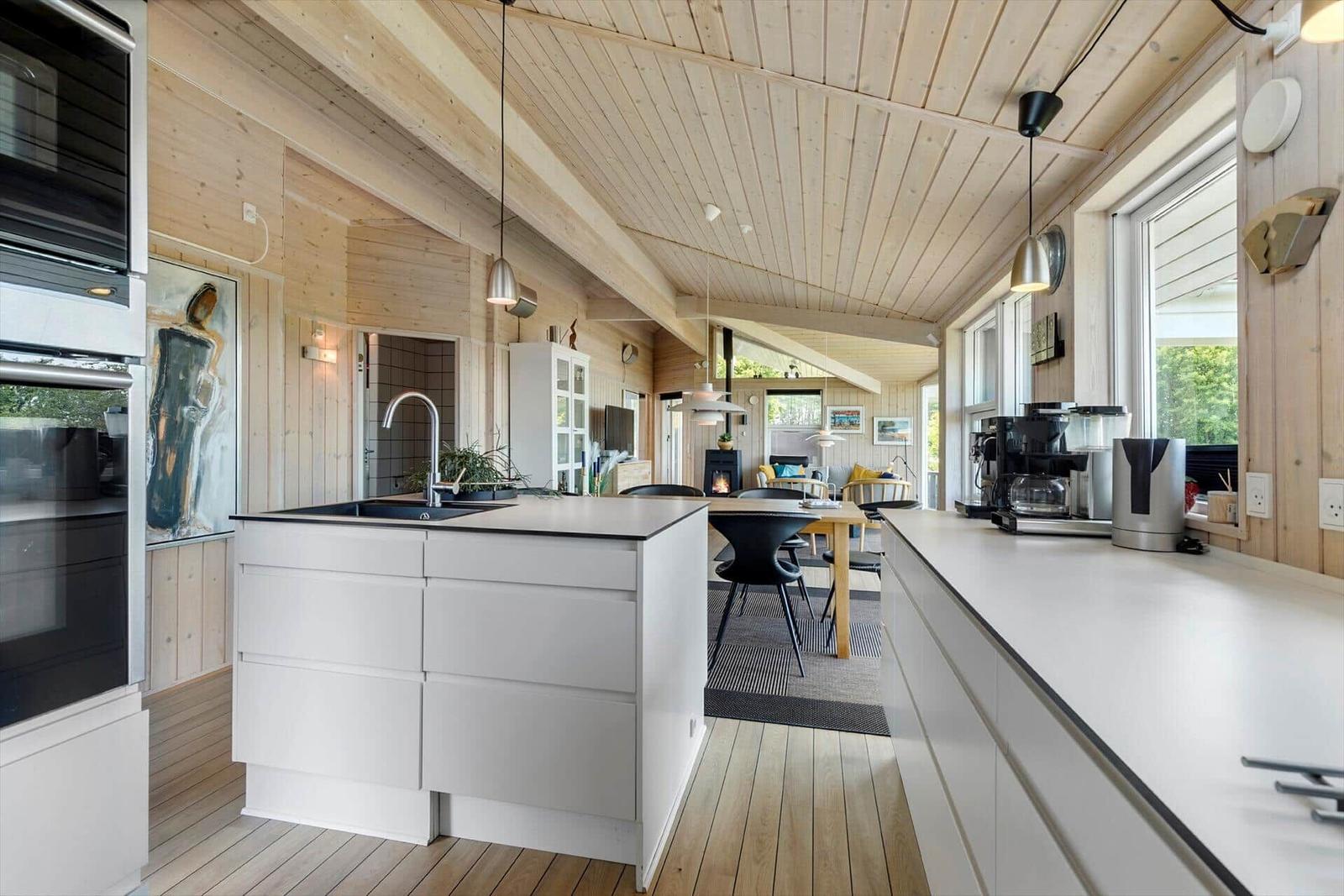 Küche mit Insel und Essbereich, Holzdecke und Fenster