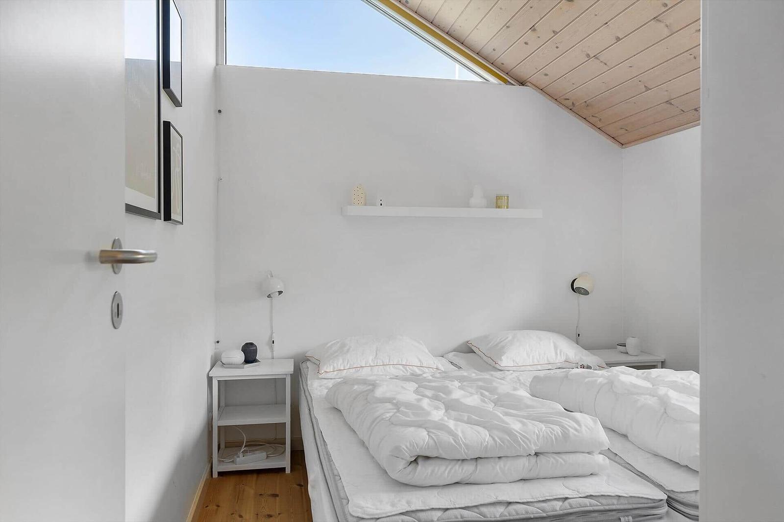 Schlafzimmer mit Doppelbett, zwei Nachttischen und Dachschrägen