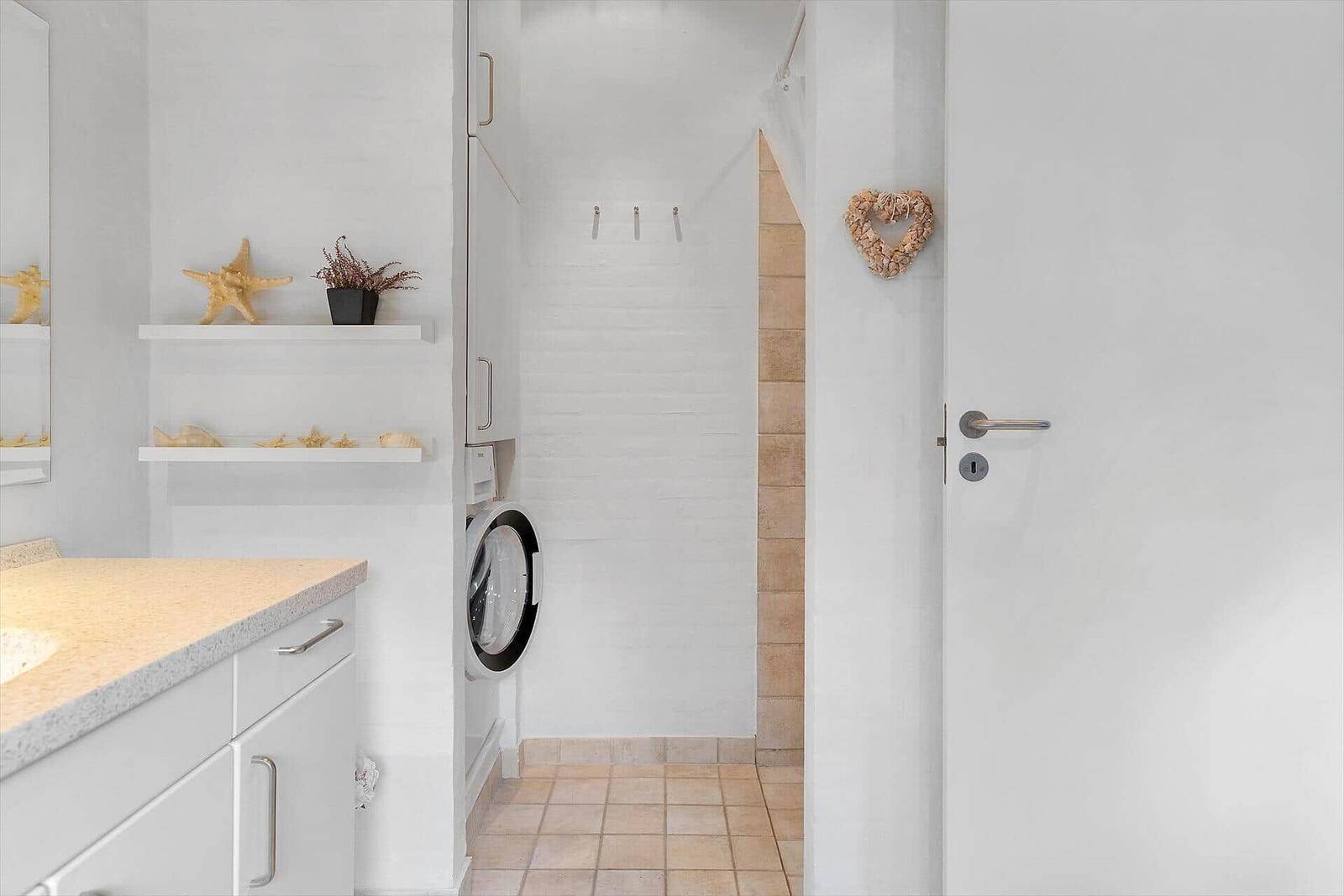 Badezimmer mit Waschmaschine, Regalen und Herz-Dekoration an der Tür.