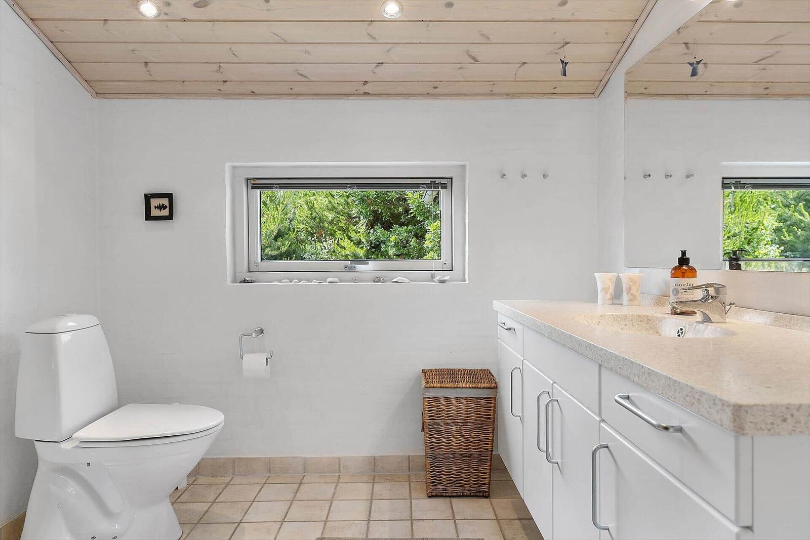 Badezimmer mit Toilette, Waschbecken und Fenster zum Garten.