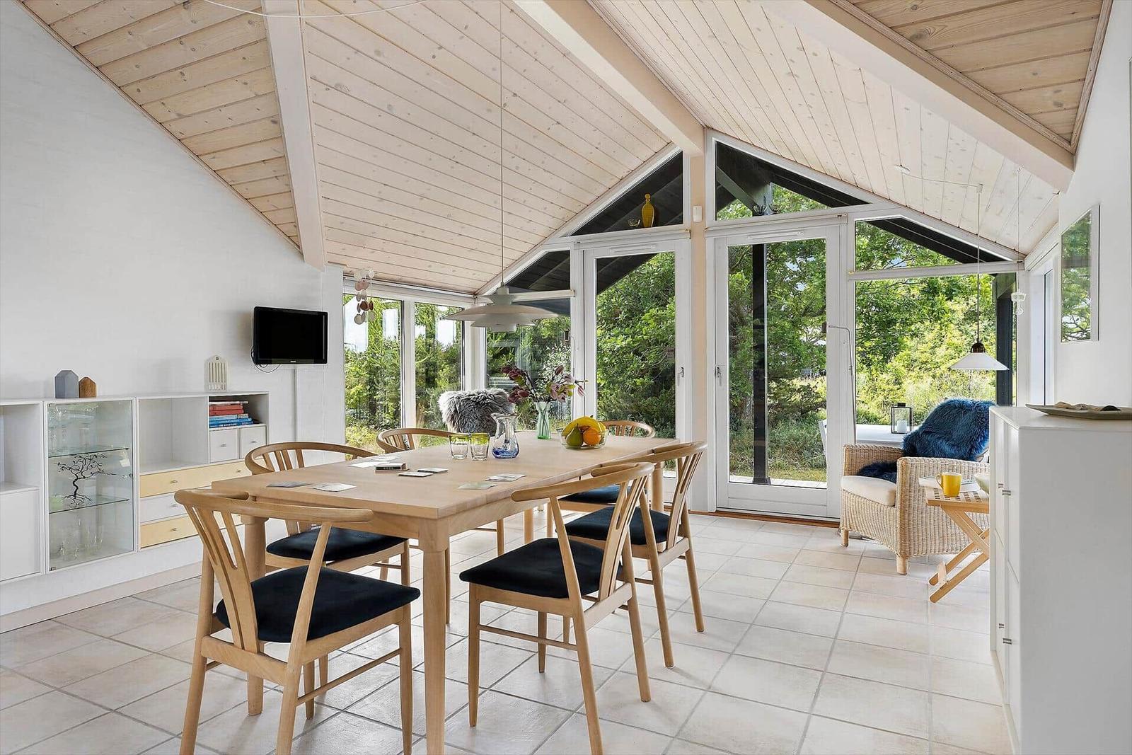 Esszimmer mit Holztisch, Stühlen und großem Fensterblick auf Garten