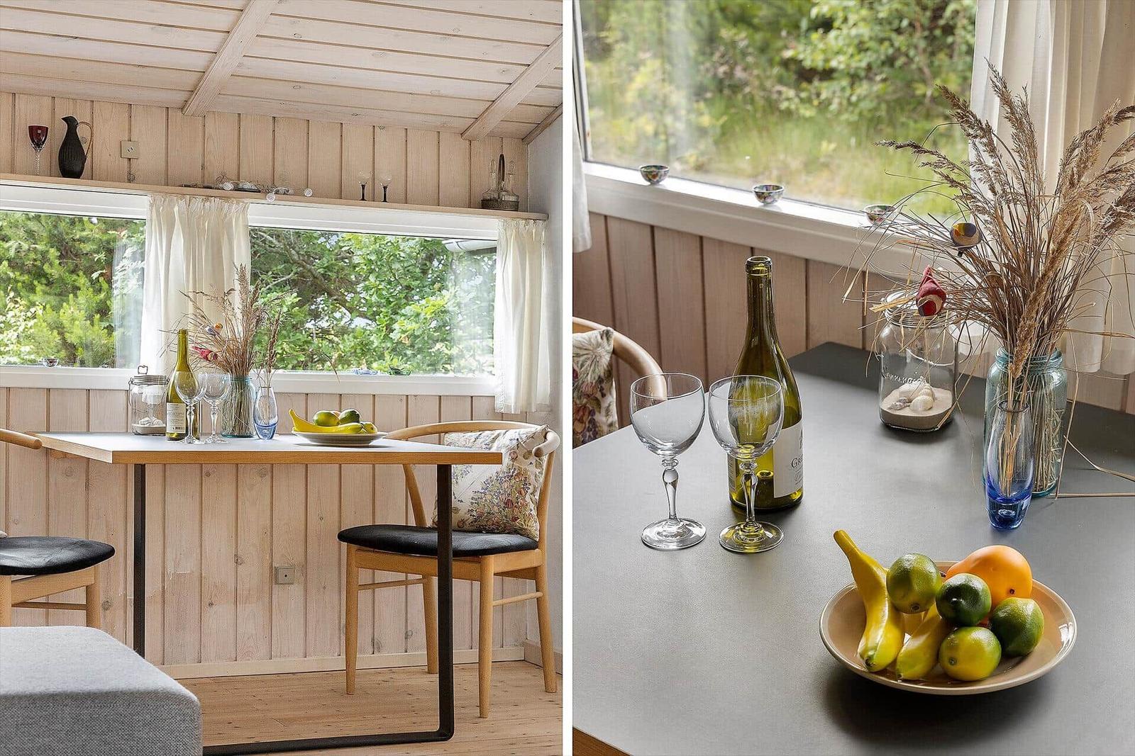 Essbereich mit Tisch, Stühlen und Fensterblick auf Grün.