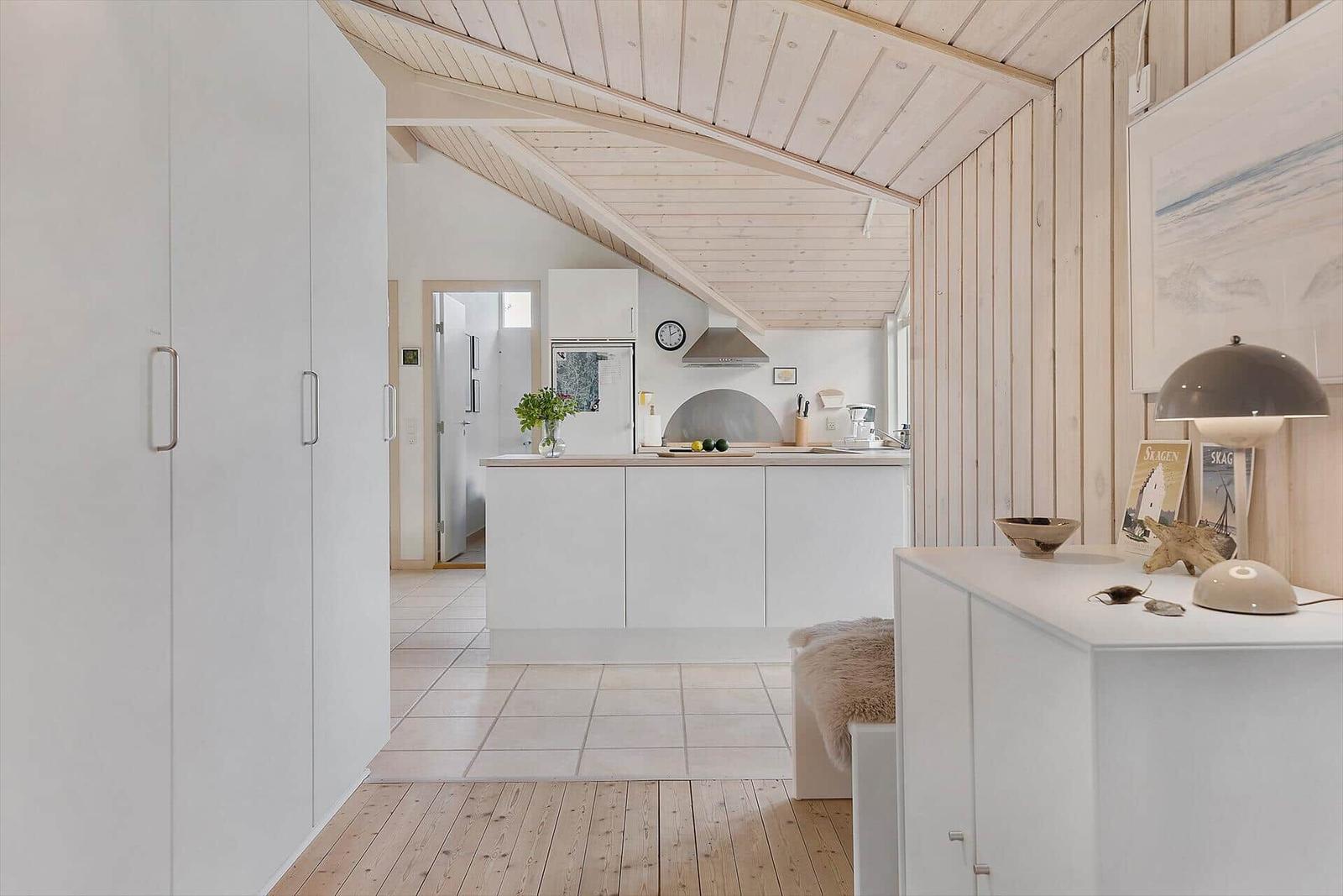Küche mit weißen Schränken und Holzdecke. Holzfußboden und Wandverkleidung.