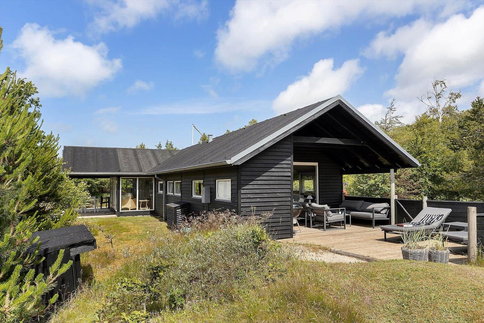 Schwarzes Holzhaus mit Terrasse und Garten. Außensitzgelegenheiten und Grillmöglichkeit.