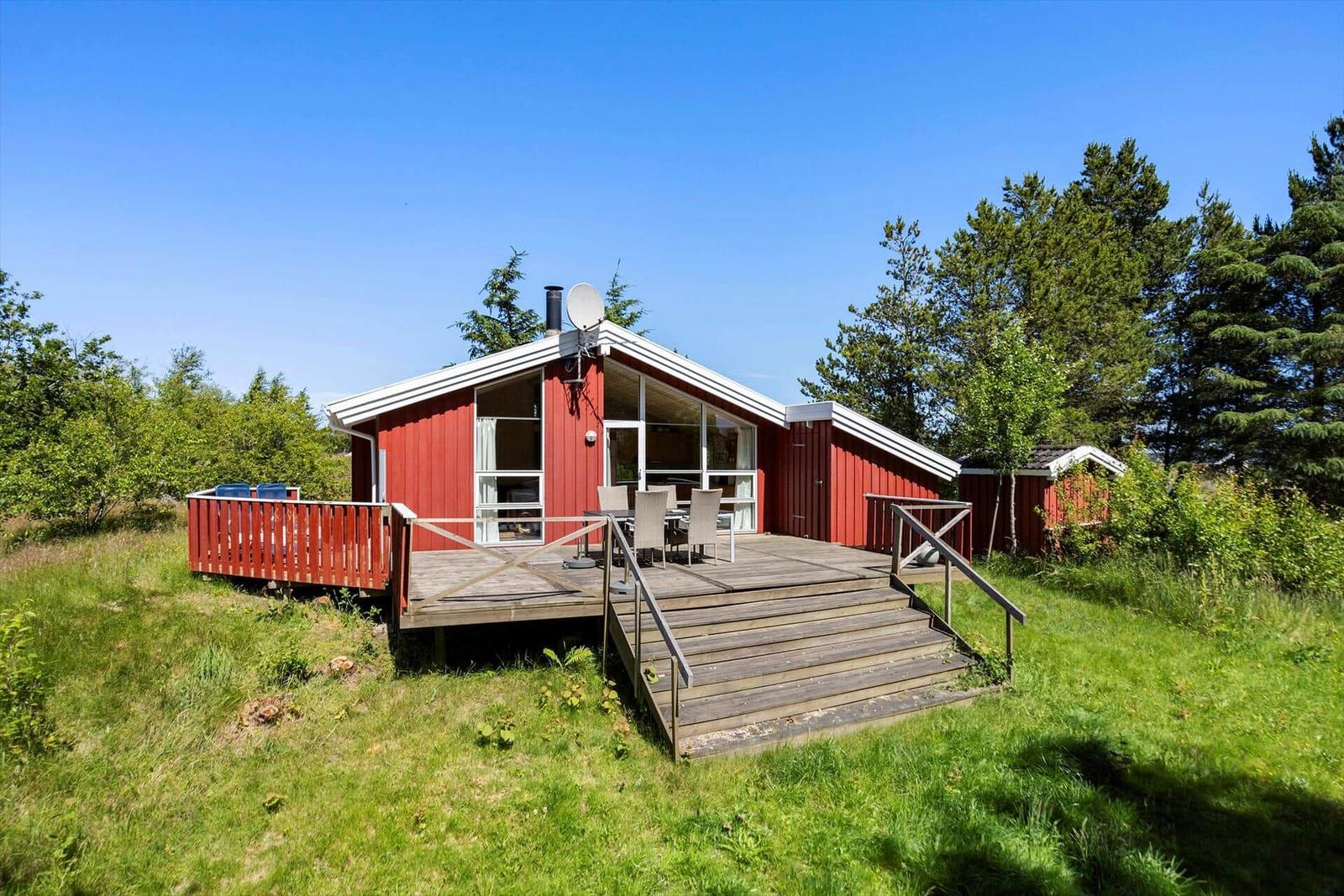 Red vacation house with terrace and stairs in the green
