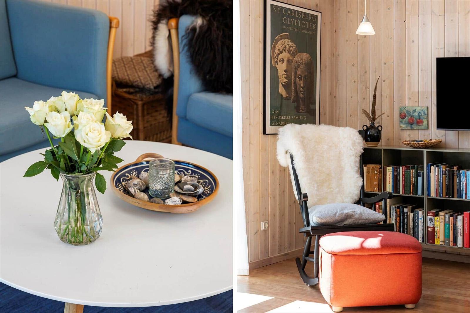 Living area with blue sofa, white tabletop, and white roses. A rocking chair with fur cover and red ottoman.