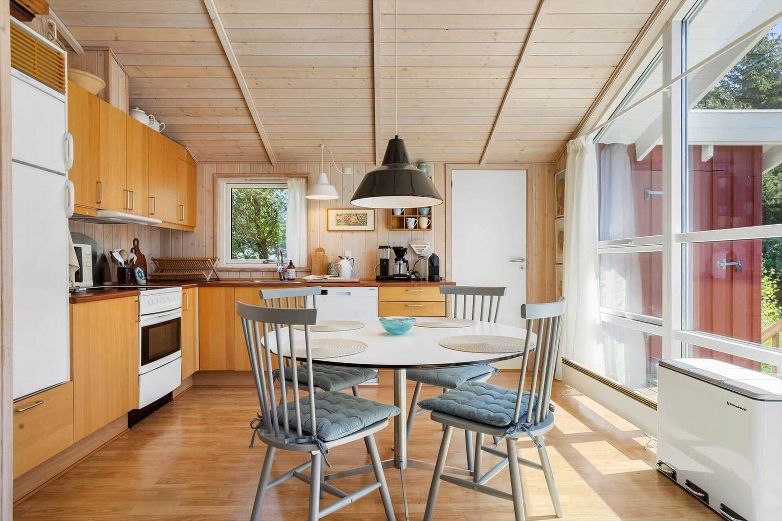 Kitchen with dining area, wooden ceiling, and large windows.