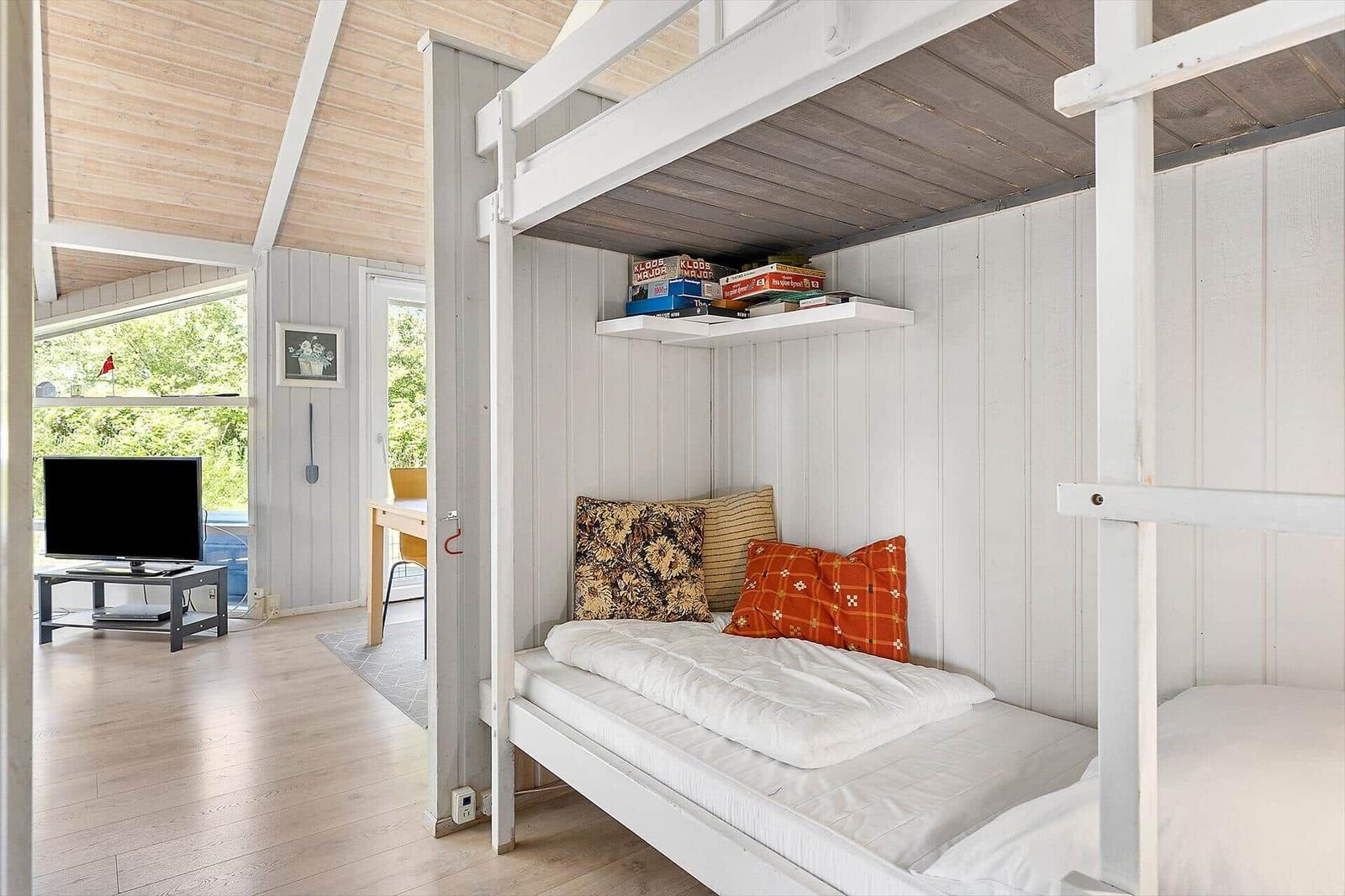Schlafzimmer mit Doppelstockbett und Bücherregal an der Wand.