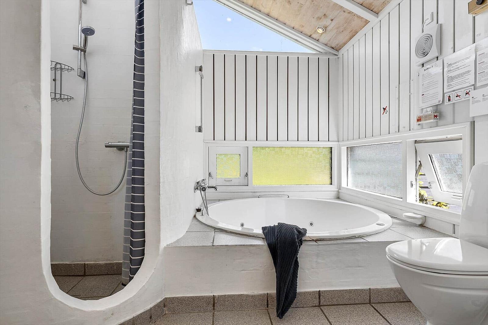 Bad mit Whirlpool, Dusche und Toilette. Fenster mit Glasmosaik.
