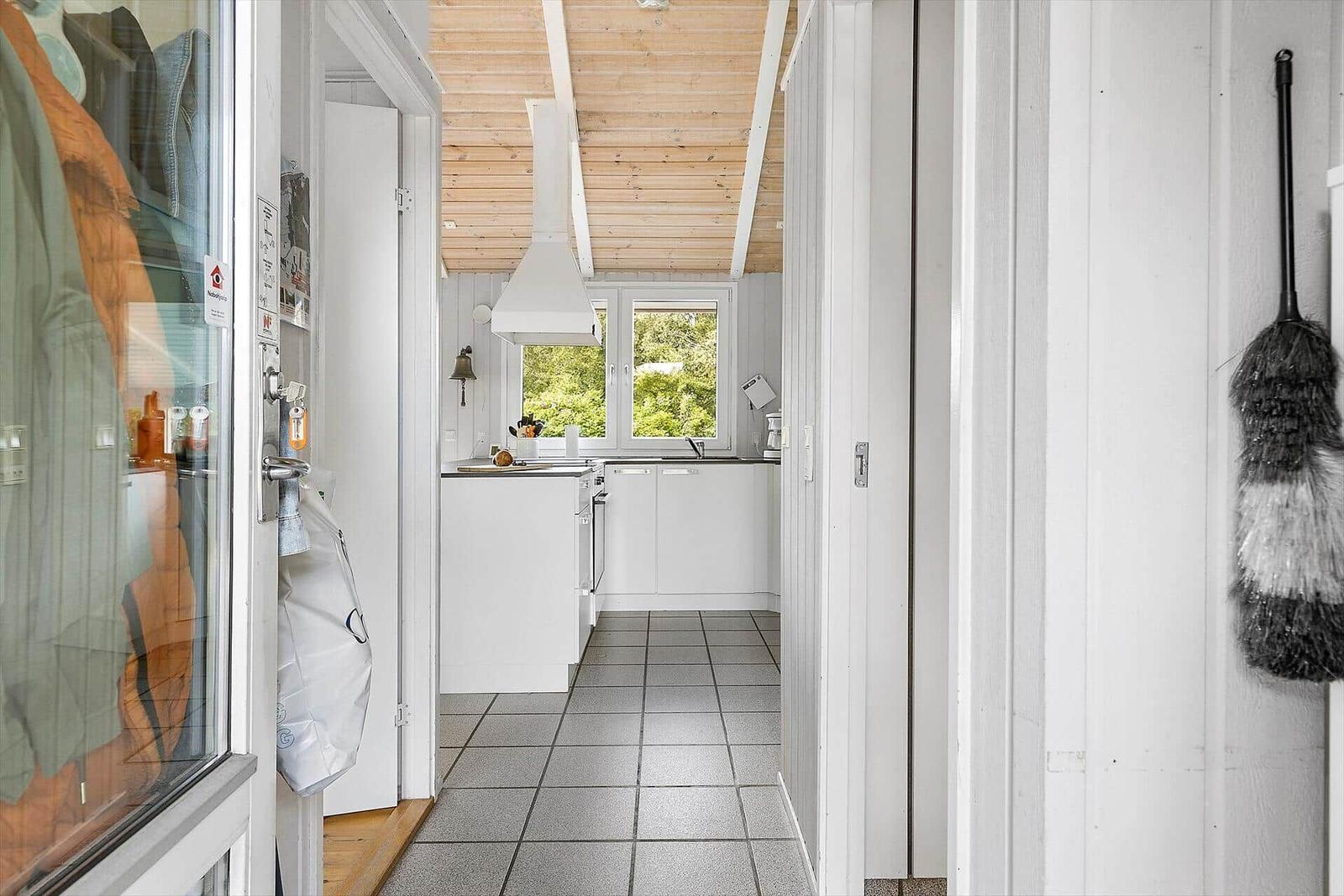 Küche mit weißer Einbauküche, Fenster und Holzdecke