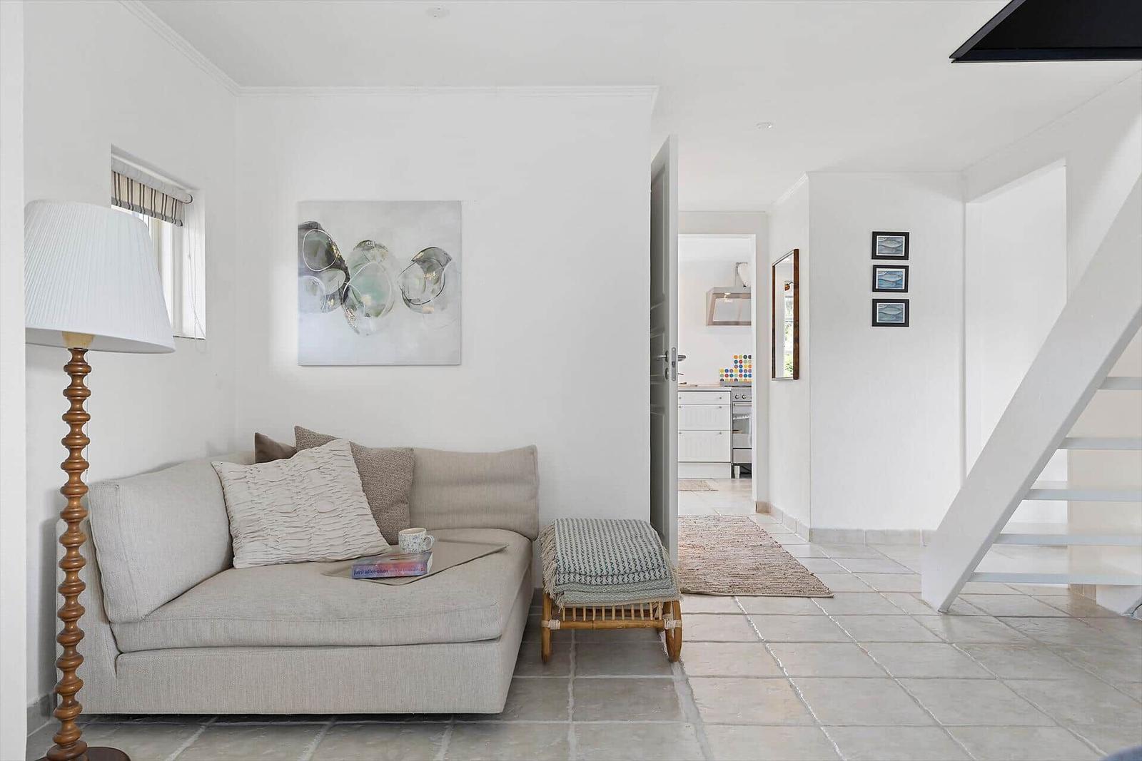 Wohnzimmer mit Sofa, Stehlampe und Blick in die Küche und auf die Treppe.