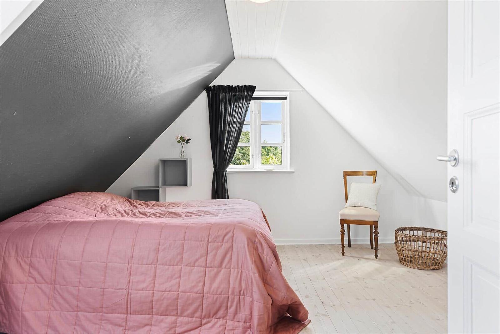 Schlafzimmer mit rosa Bett, Holzboden und schwarzem Dach