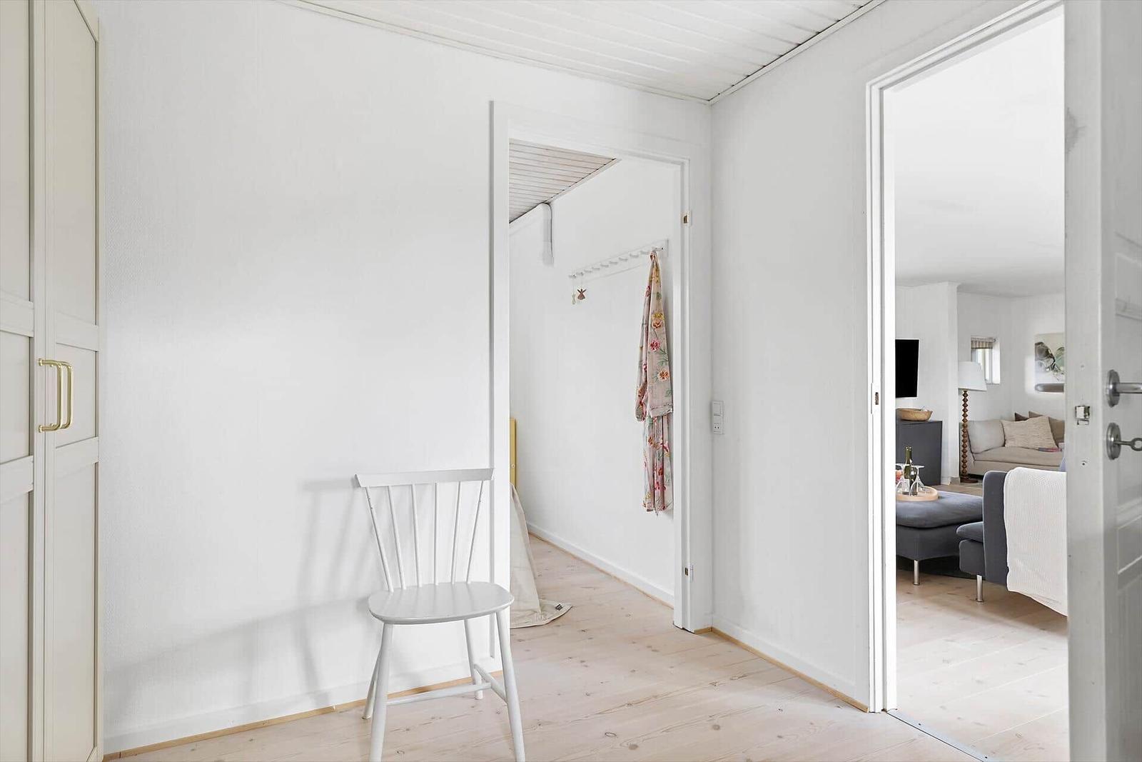Hallenbereich mit Stuhl und Blick in Wohnzimmer und Flur.