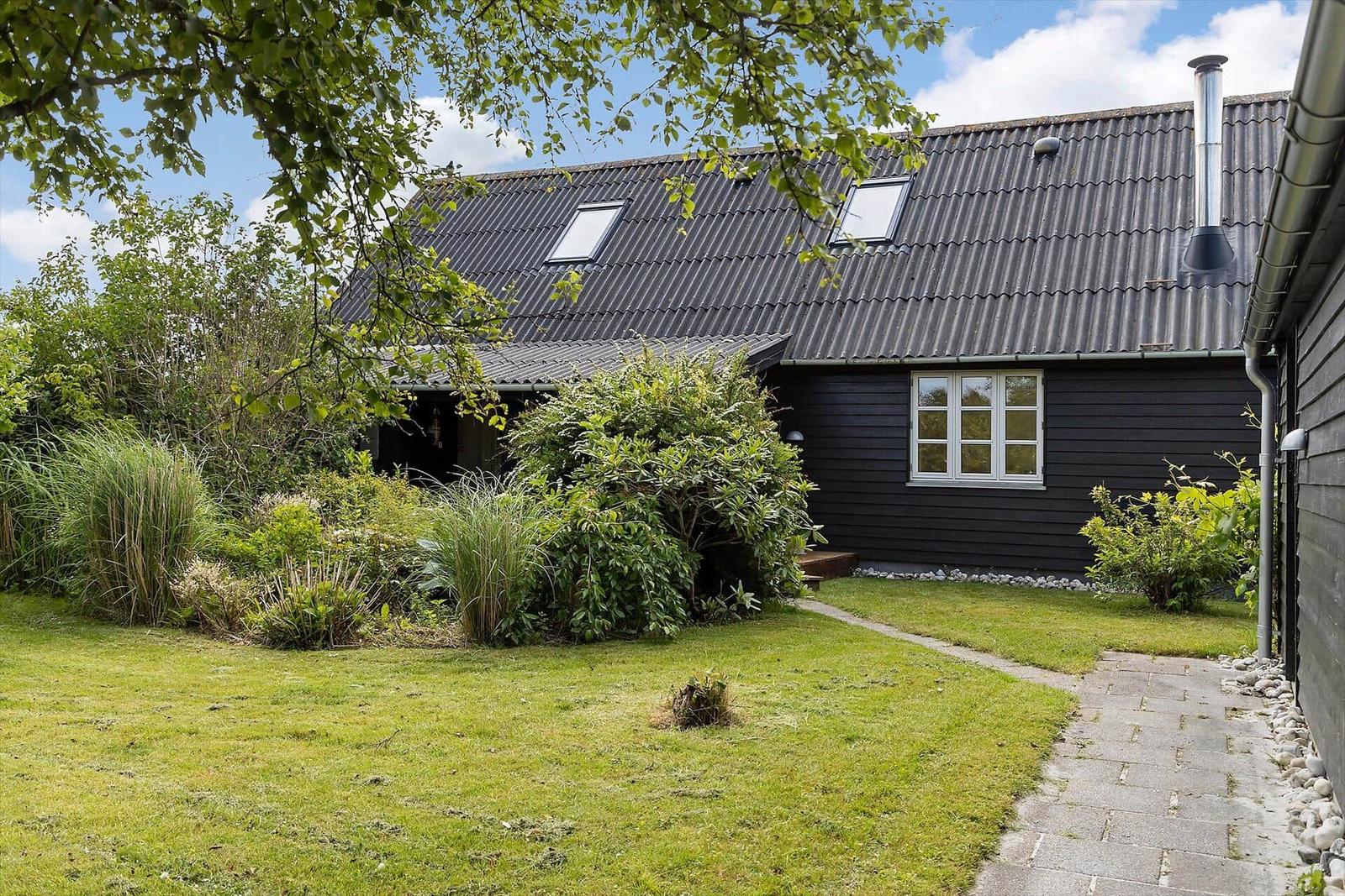 Schwarzes Holzhaus mit Dachgauben und Gartenweg.