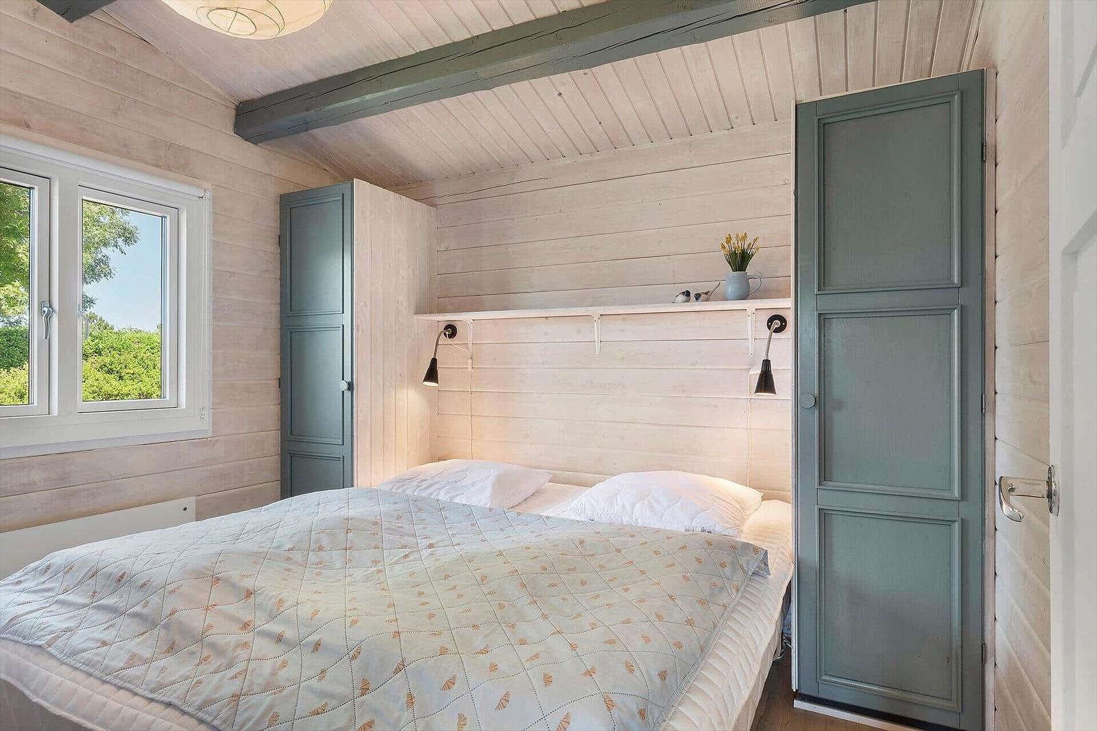 Bedroom with bed, window, and green doors.