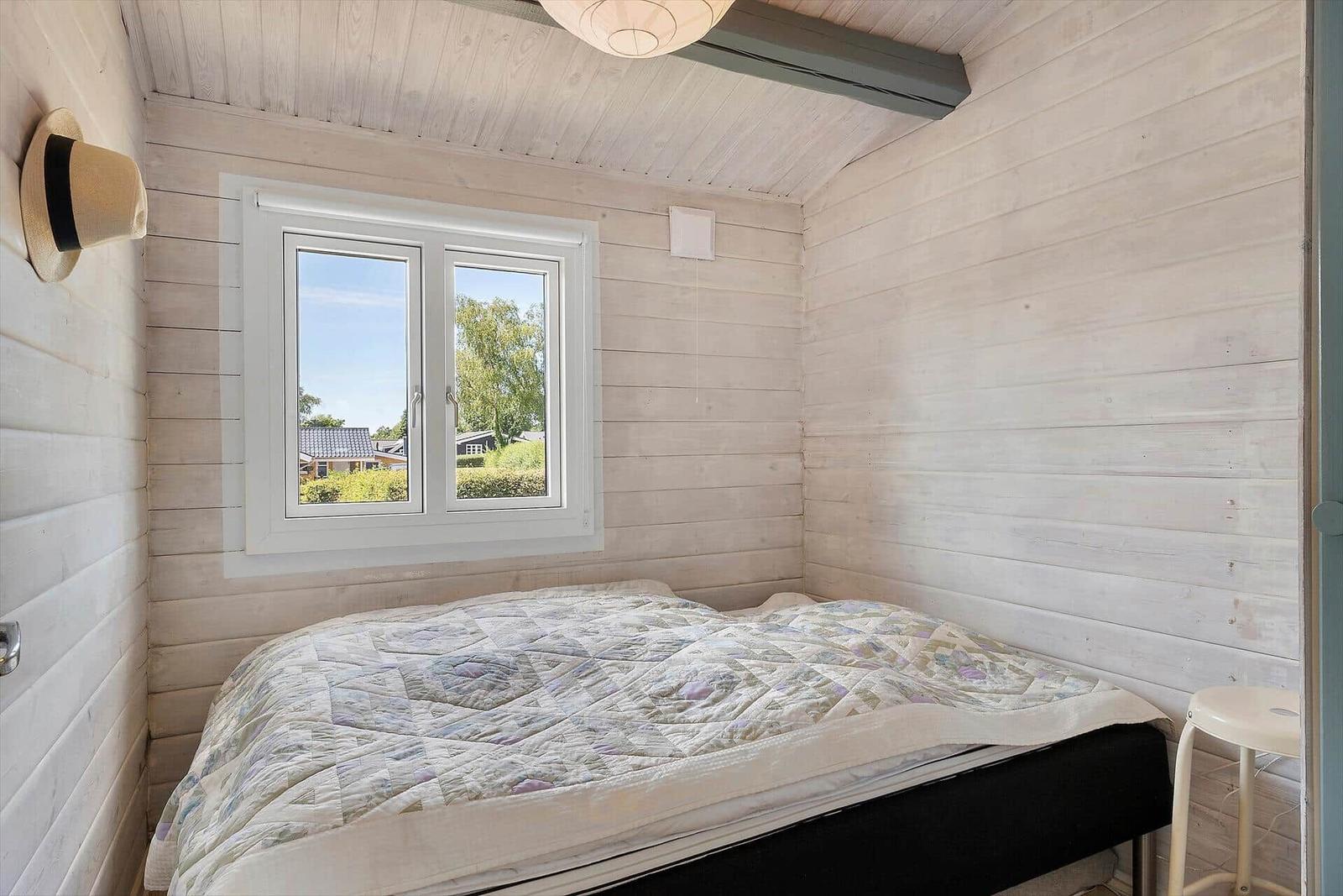 Bedroom with bed, window, and wood paneling.